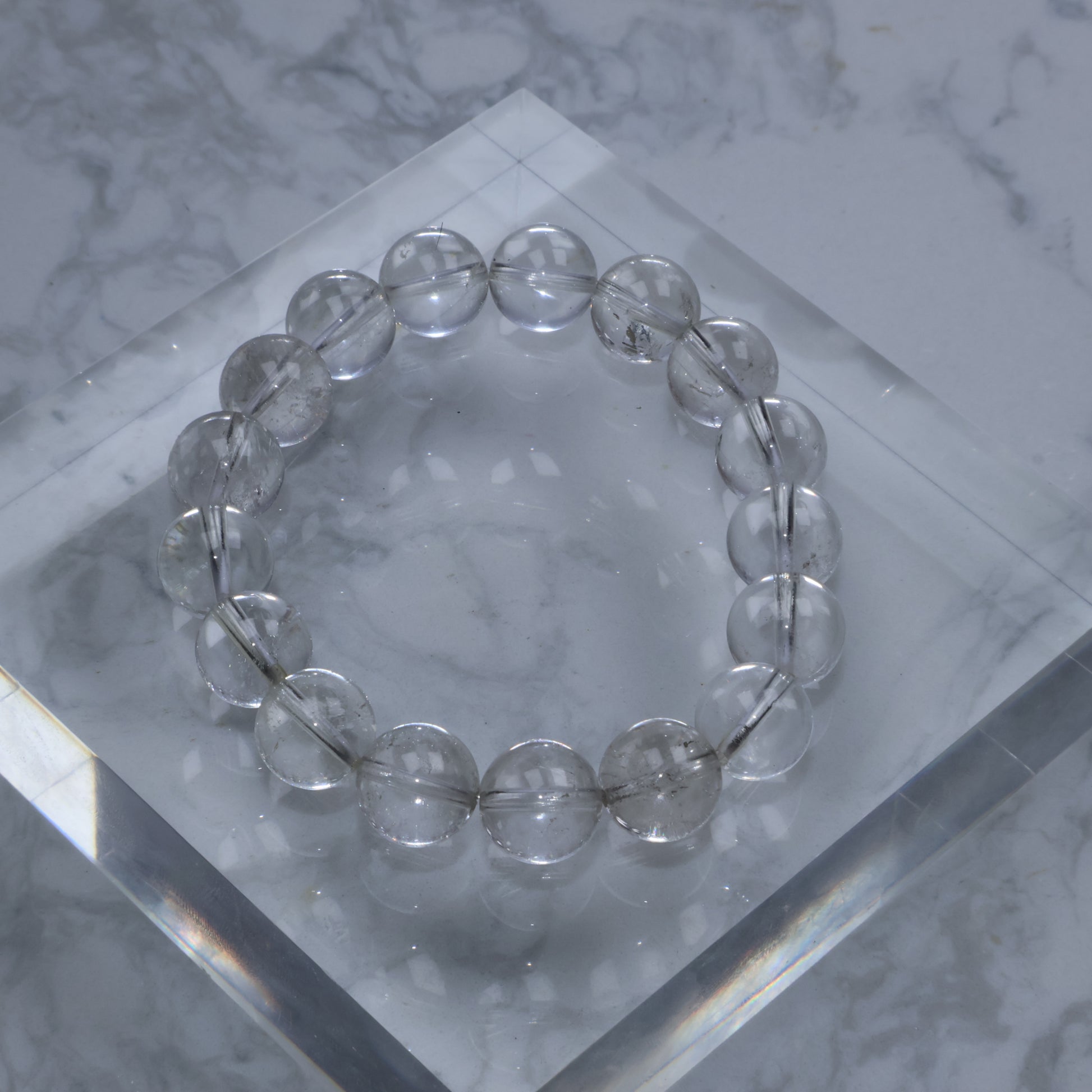 Top-down view of Clear Quartz bracelet on a clear acrylic block