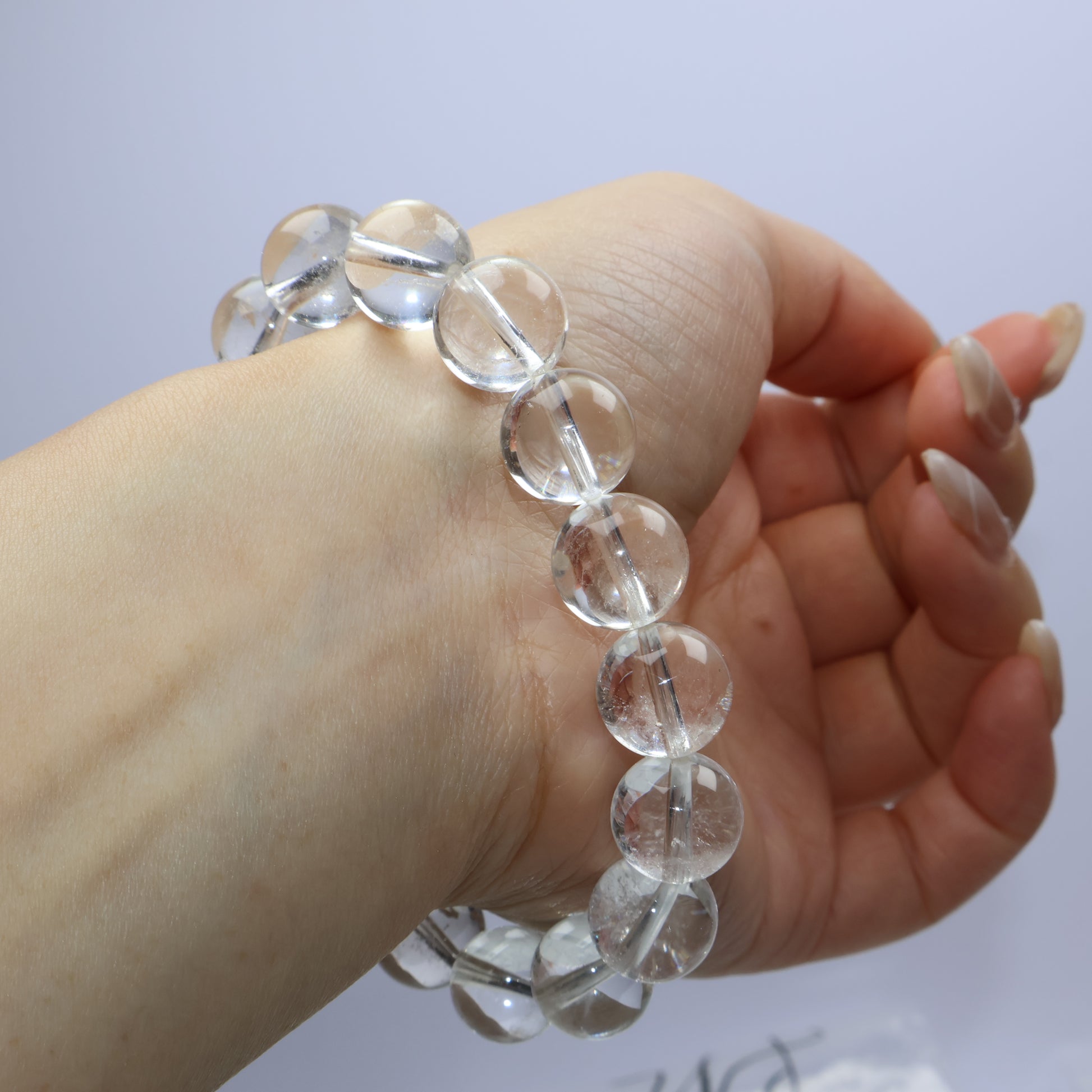 Hand twist pose showing beads shimmering under soft light