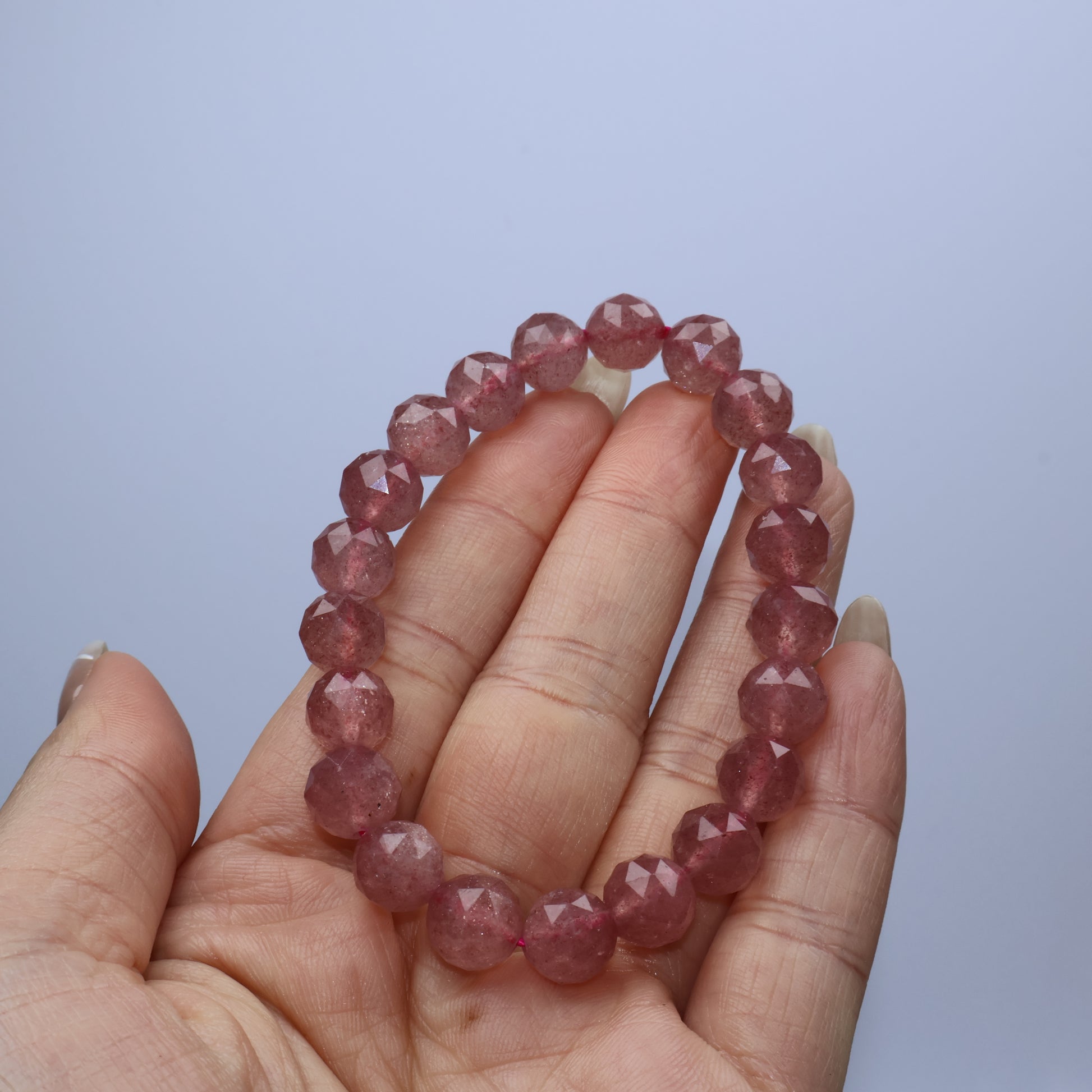 Handheld view of Strawberry Quartz bracelet showing soft, uniform pink tones