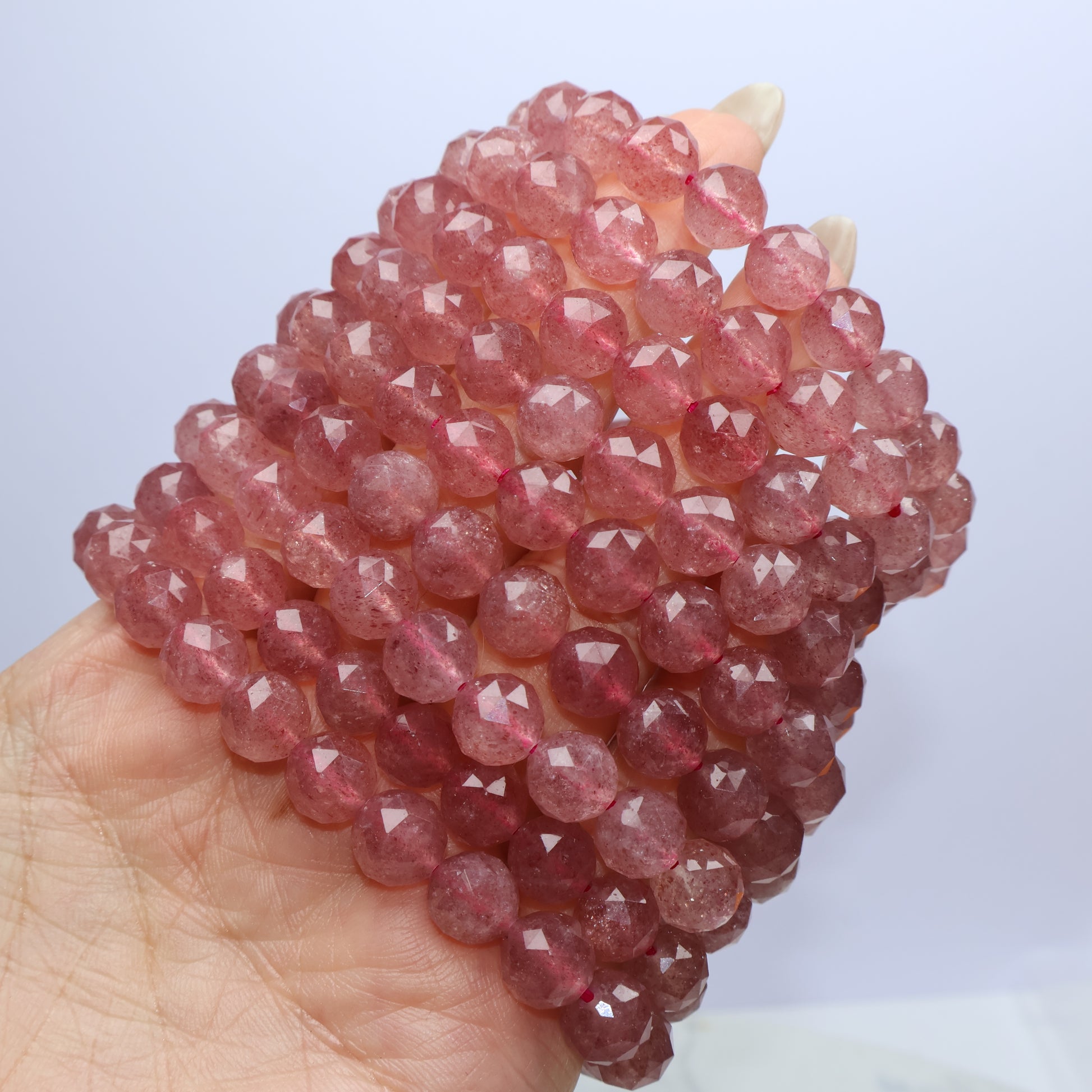 Multiple Strawberry Quartz bracelets stacked in hand