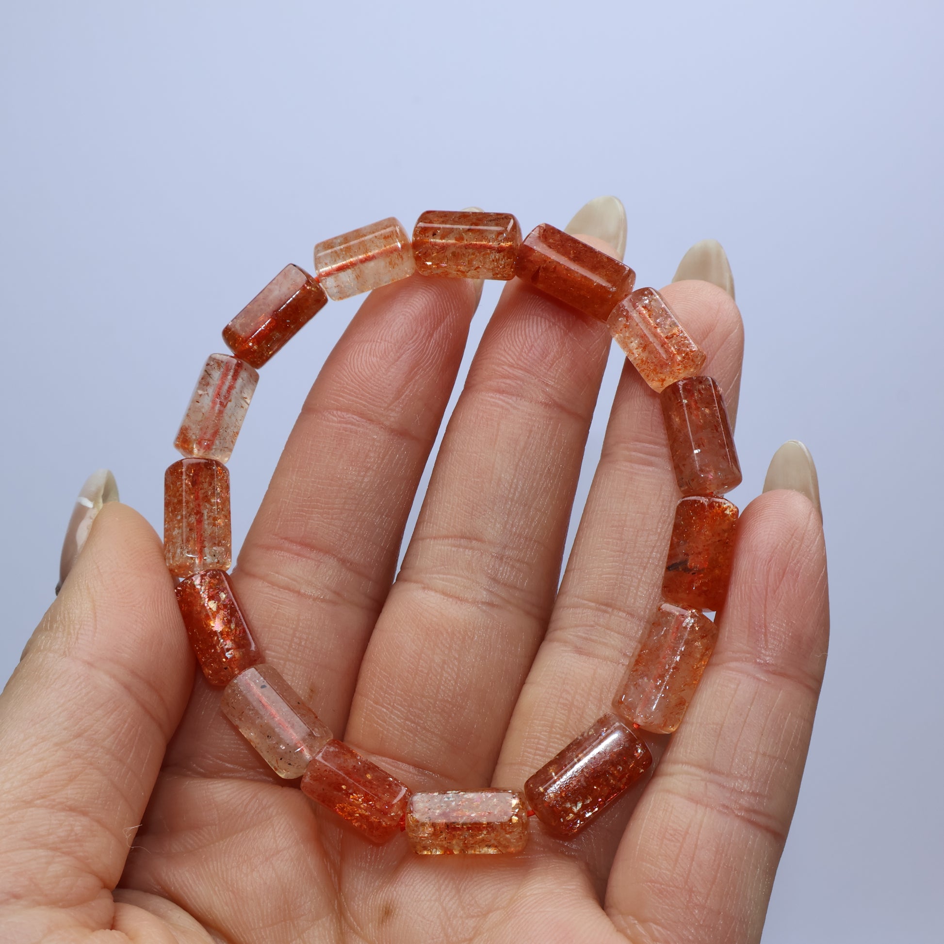Handheld display of full Sunstone bracelet showing uniform barrel bead arrangement