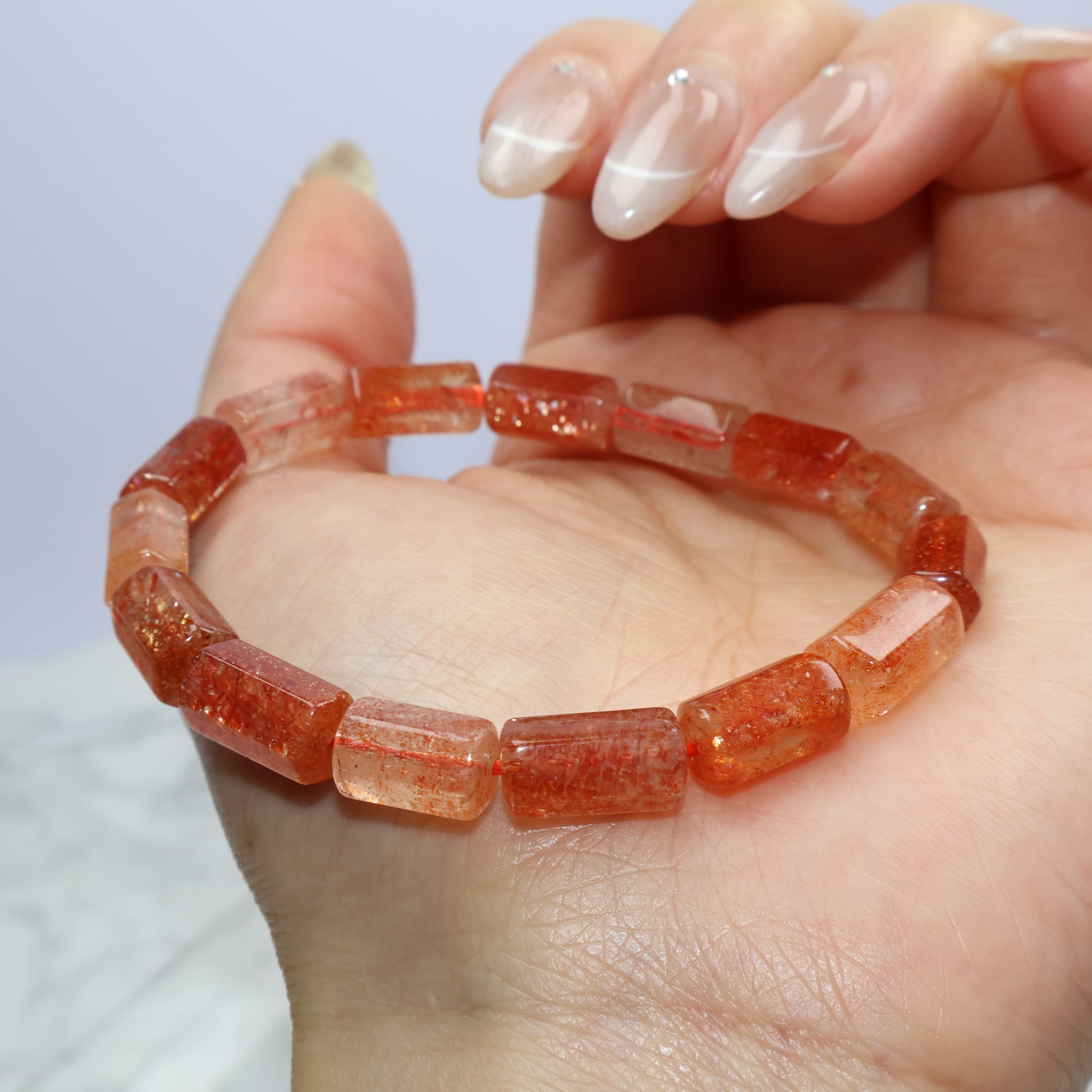 Sunstone bracelet resting on palm, showing radiant orange glow and bead clarity