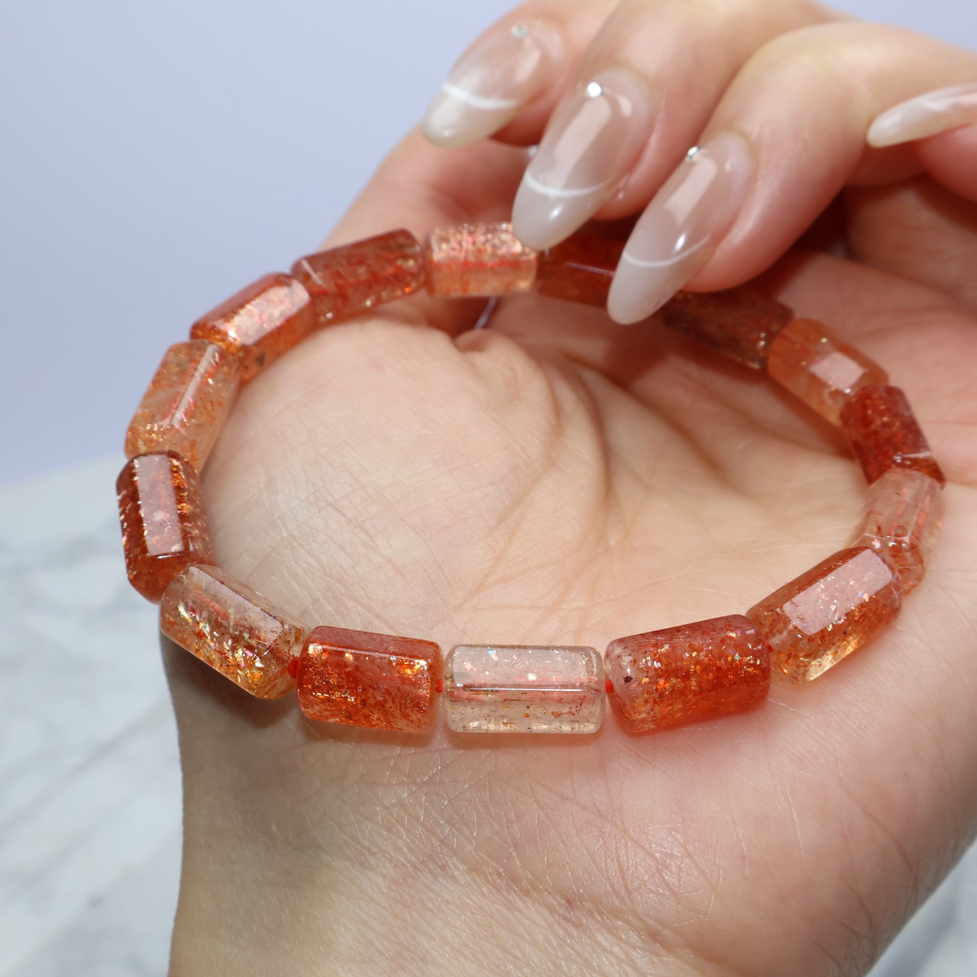 Sunstone bracelet cradled in hand, reflecting light off polished barrel beads