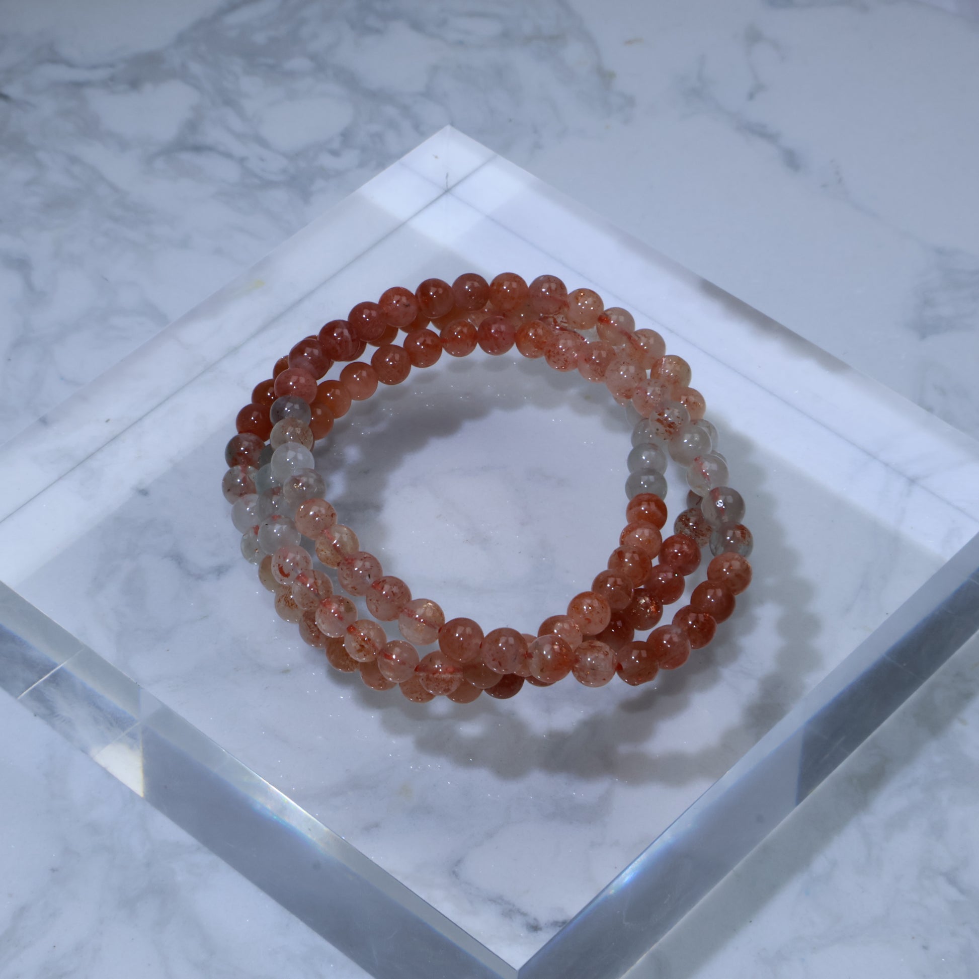 Top-down photo of Arusha Sunstone triple wrap bracelet on clear acrylic block