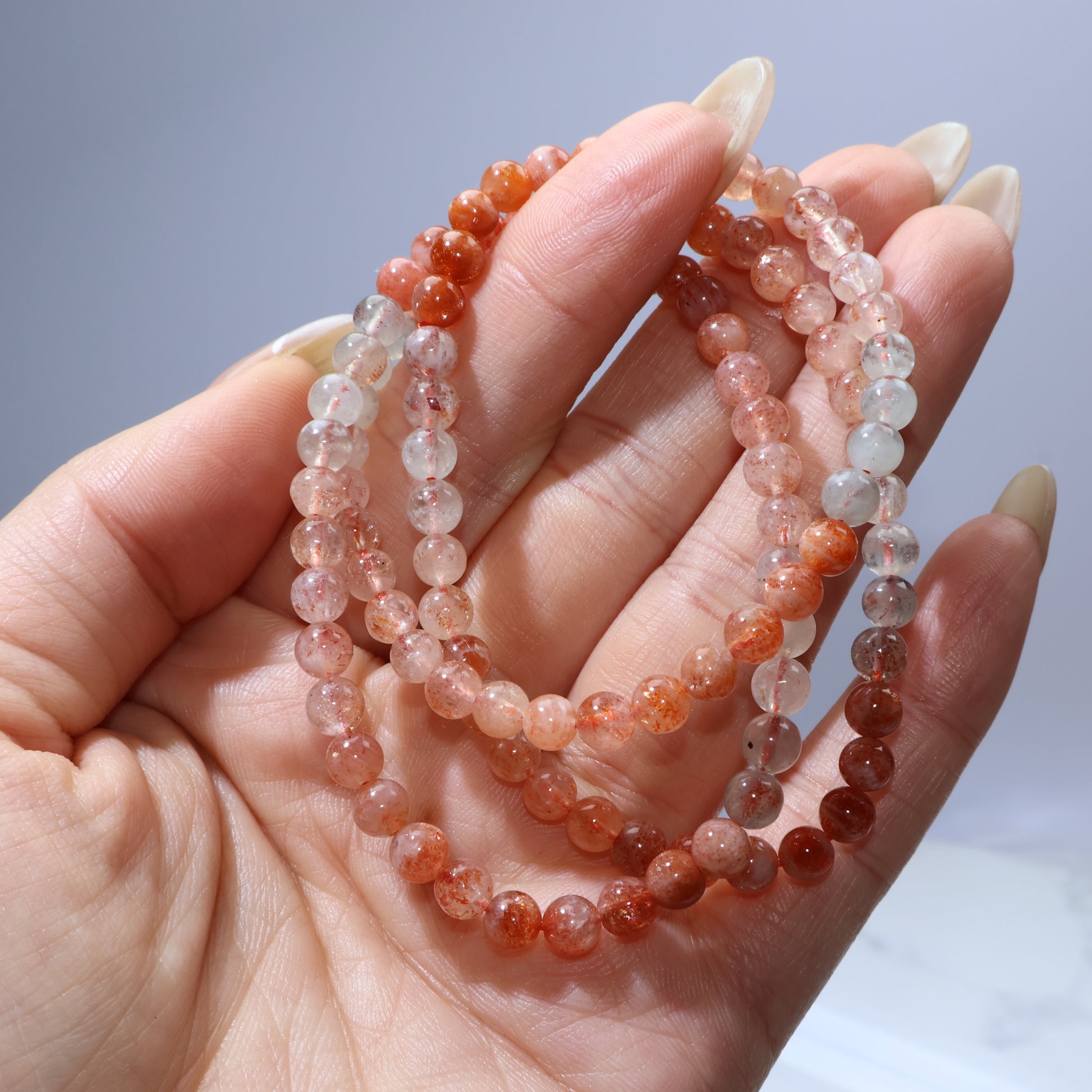 Handheld close-up of the warm orange beads with visible coppery inclusions