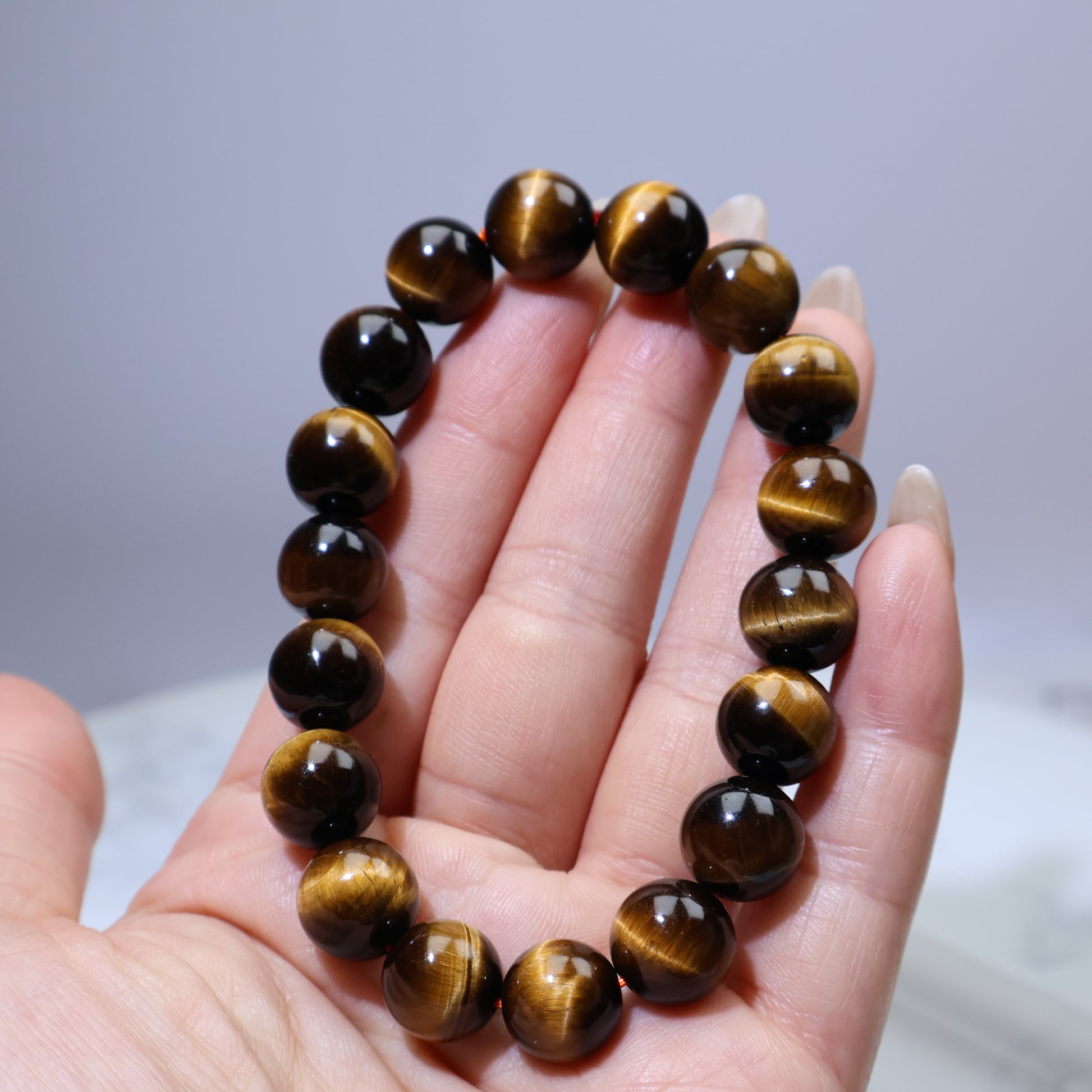 Handheld view of Tiger’s Eye bracelet with polished round beads and rich golden streaks