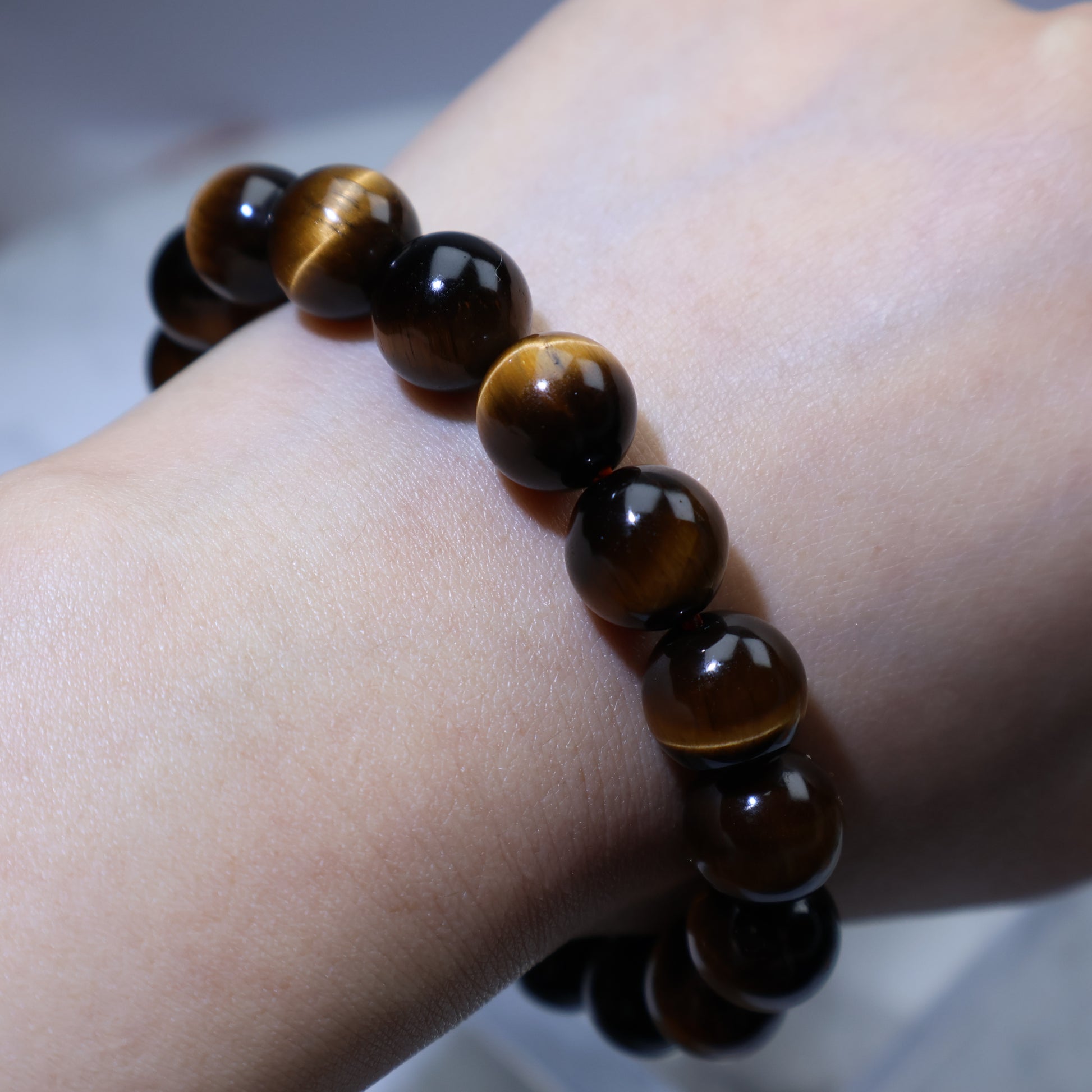 Side wrist view of Tiger’s Eye bracelet, emphasizing smooth polish and depth of color