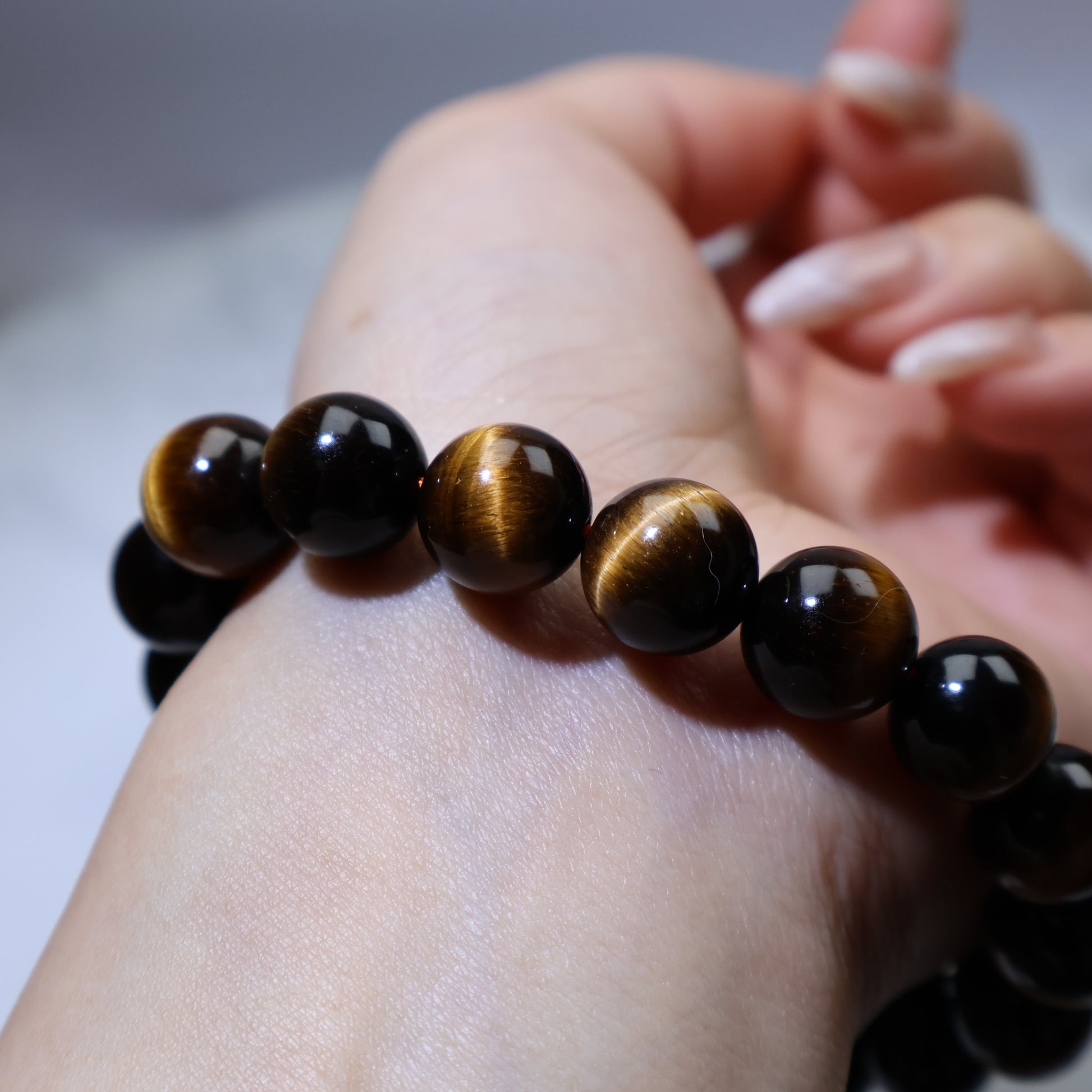 Macro shot of beads in hand, focusing on detailed golden streaks and shine