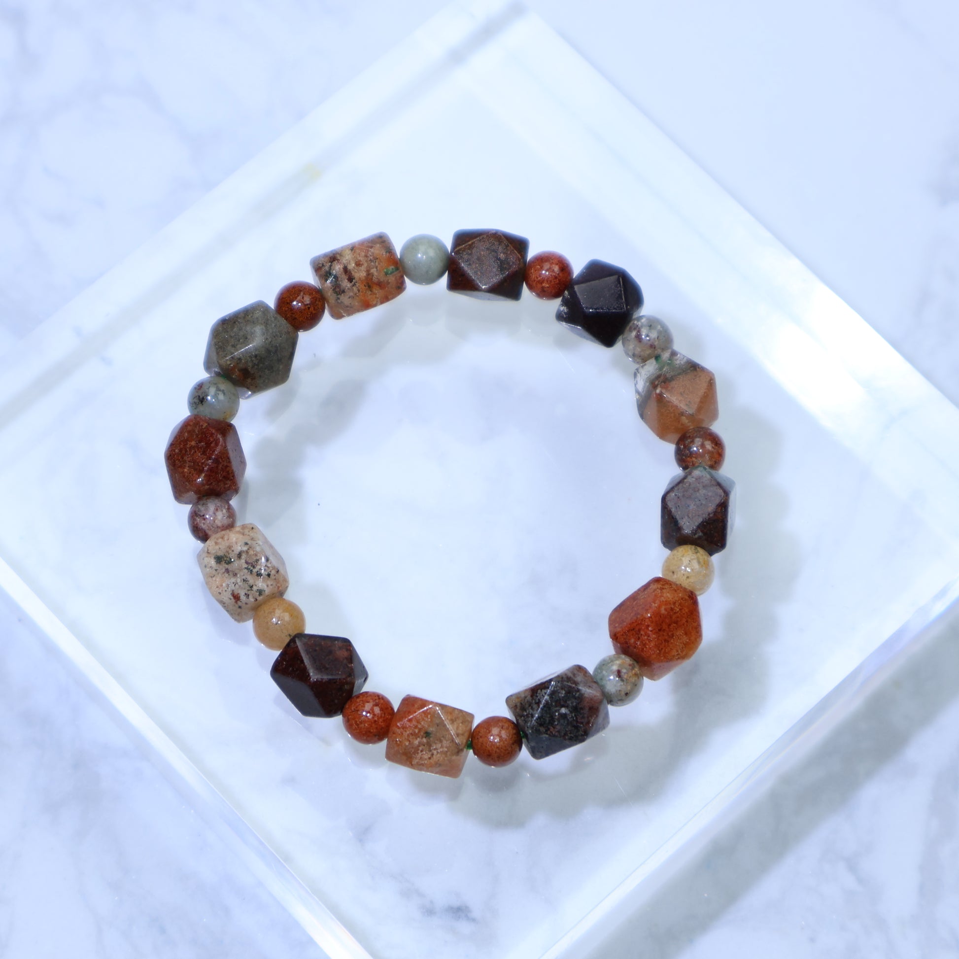 Top-down view of multi-phantom faceted bracelet on clear acrylic block