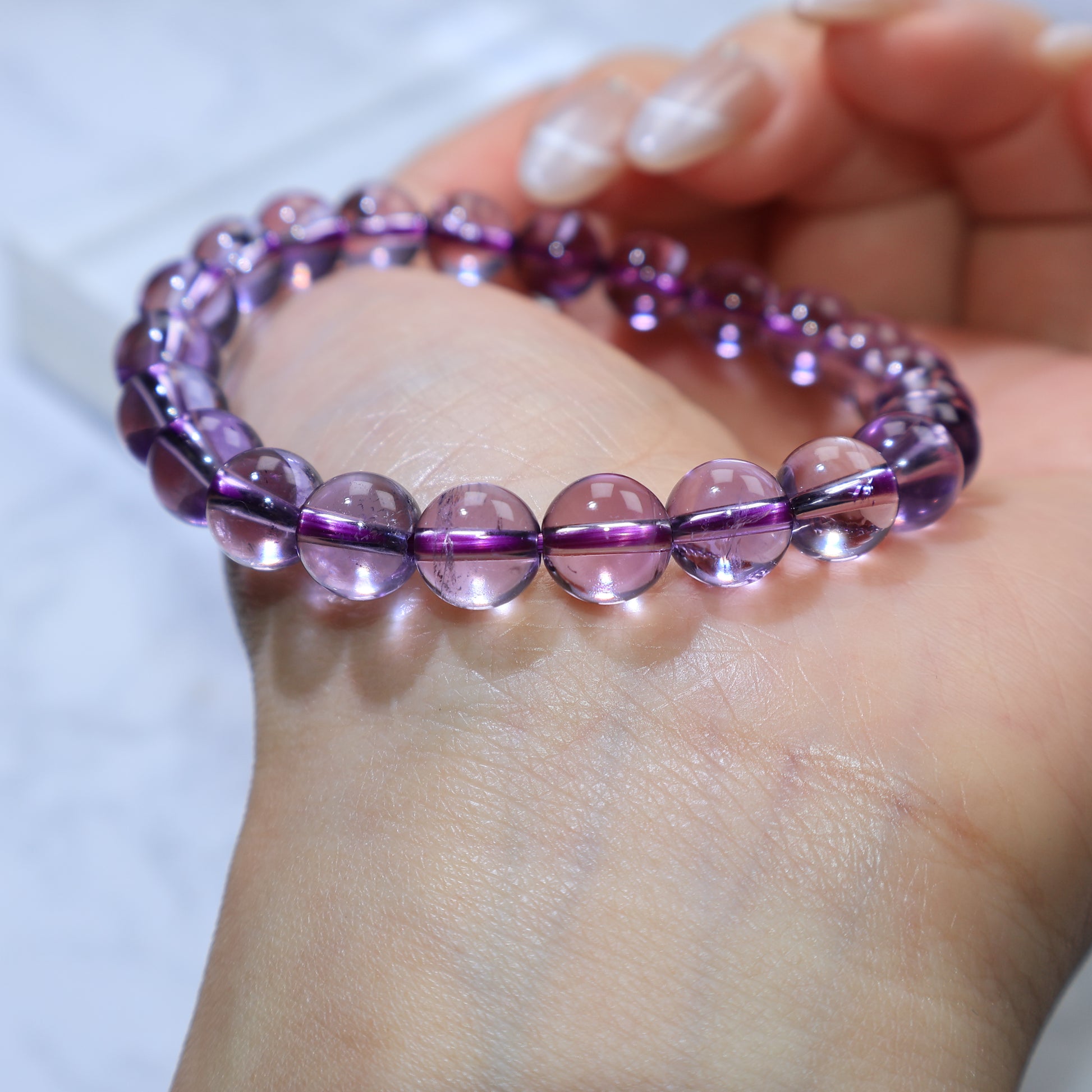 Wrist shot of bracelet under bright light, highlighting translucent violet beads