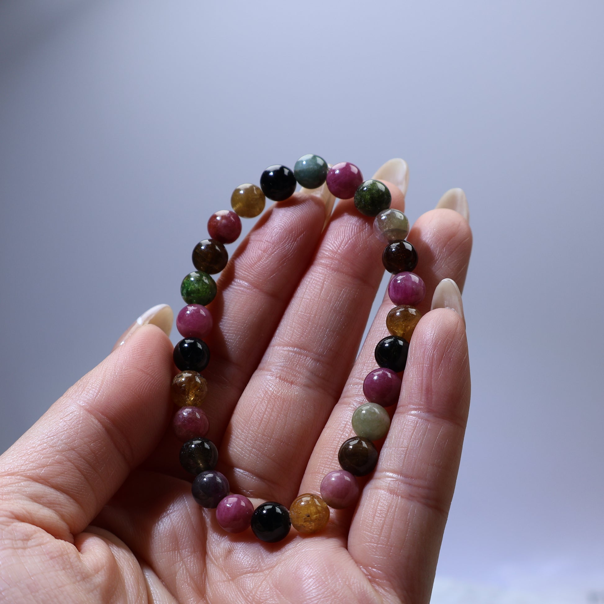 Handheld view of Multicolor Tourmaline bracelet, highlighting polished surface and natural color variations