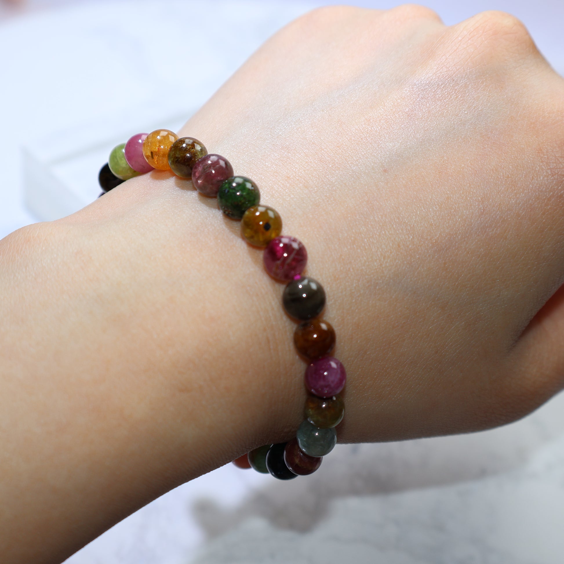 Wrist shot of bracelet under bright light, beads glowing with mixed hues