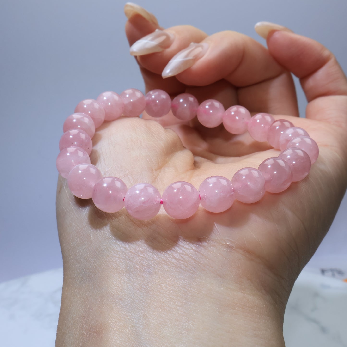 Madagascar Rose Quartz bracelet displayed across the back of hand, showing bead size and natural texture.