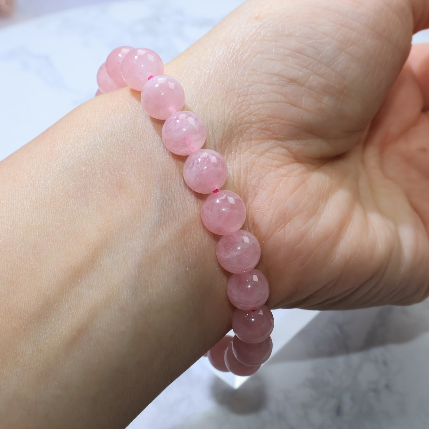 Front wrist view of Madagascar Rose Quartz bracelet, emphasizing soft romantic pink hue.