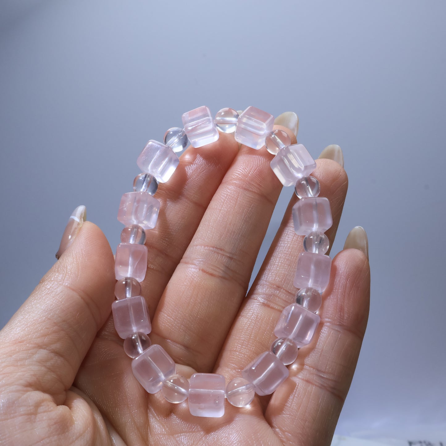 Handheld view of Rose Quartz bracelet highlighting the mix of square and round beads with gentle blush-pink color.