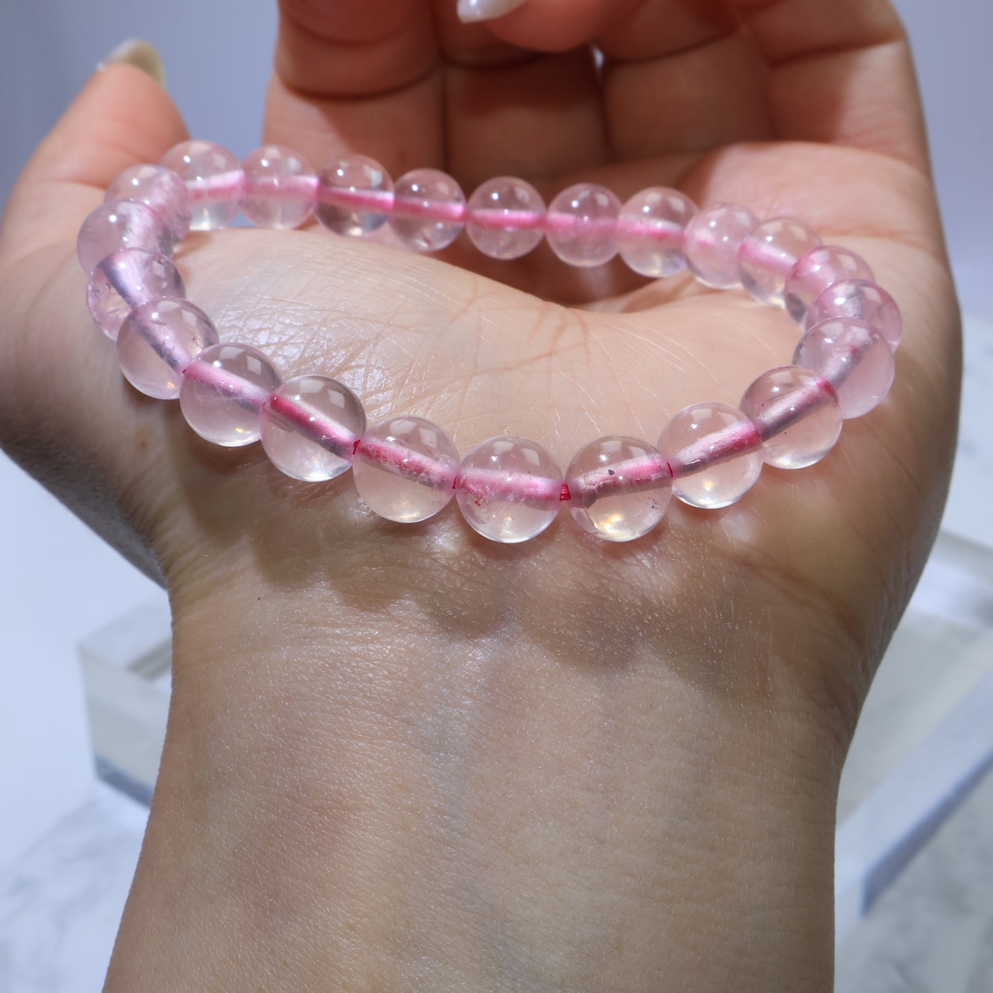 Rose Quartz bracelet displayed across the back of the hand, showing snug fit for 15cm wrist size.