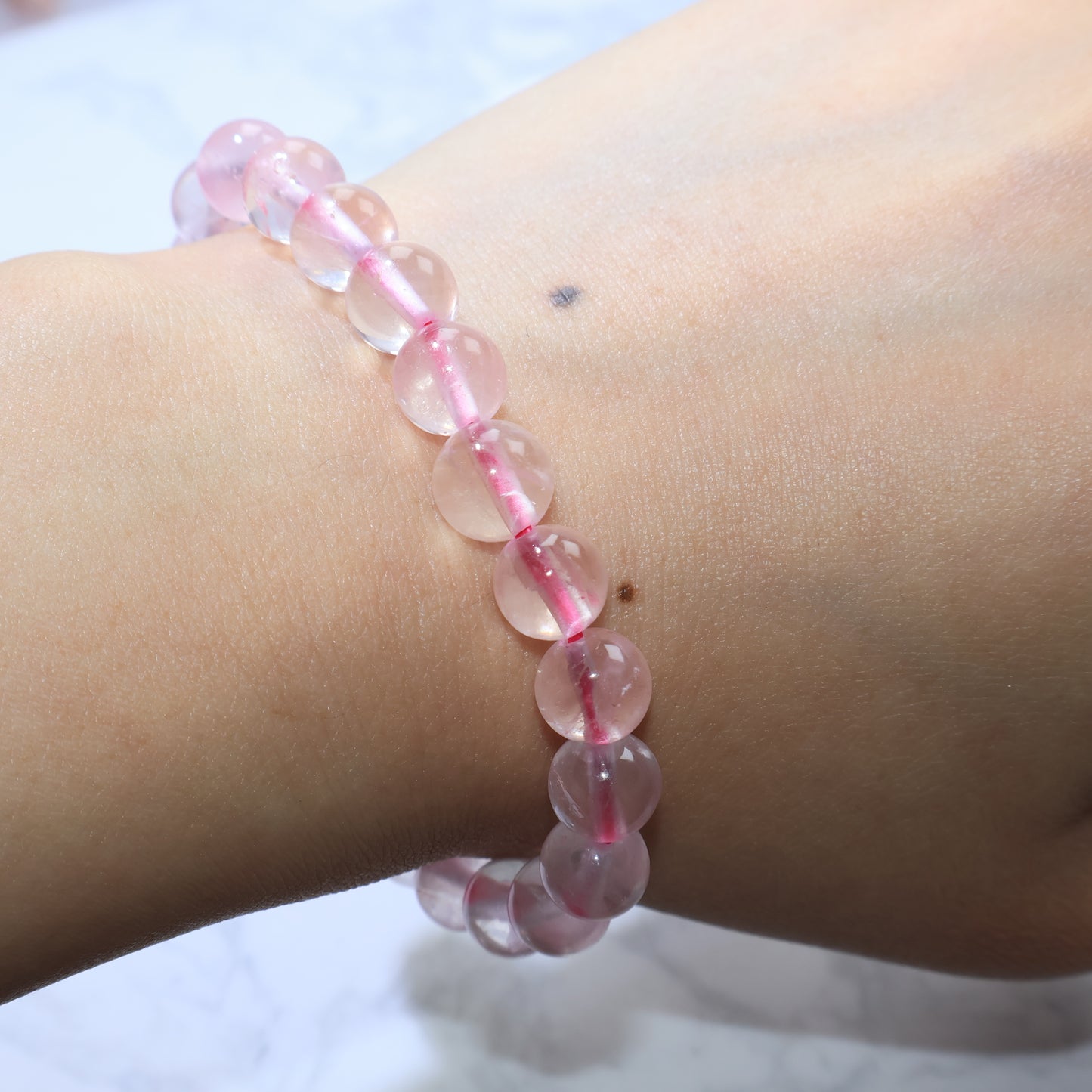 Side wrist view of Rose Quartz bracelet, showing natural clarity with ice crack patterns.