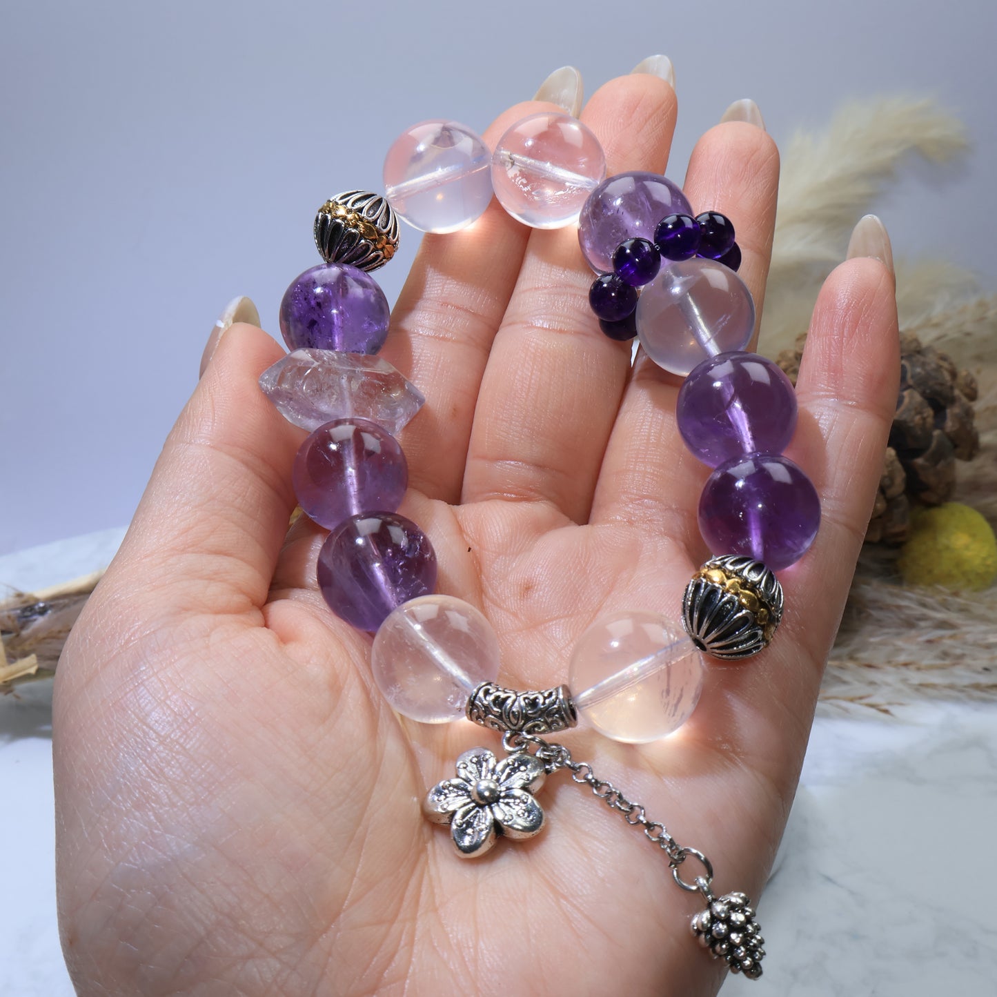 Handheld overall view revealing 15 mm rose quartz, amethyst rounds, the DT amethyst point, and copper caps/bail with chain charm.