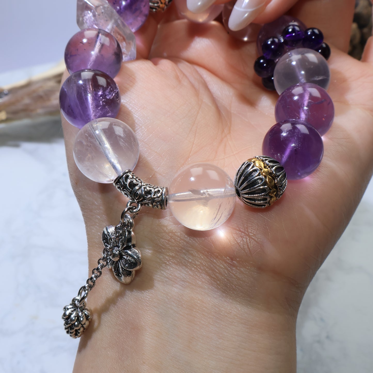 Close-up on the carved copper bail with pine cone dangle next to rose quartz and amethyst beads.