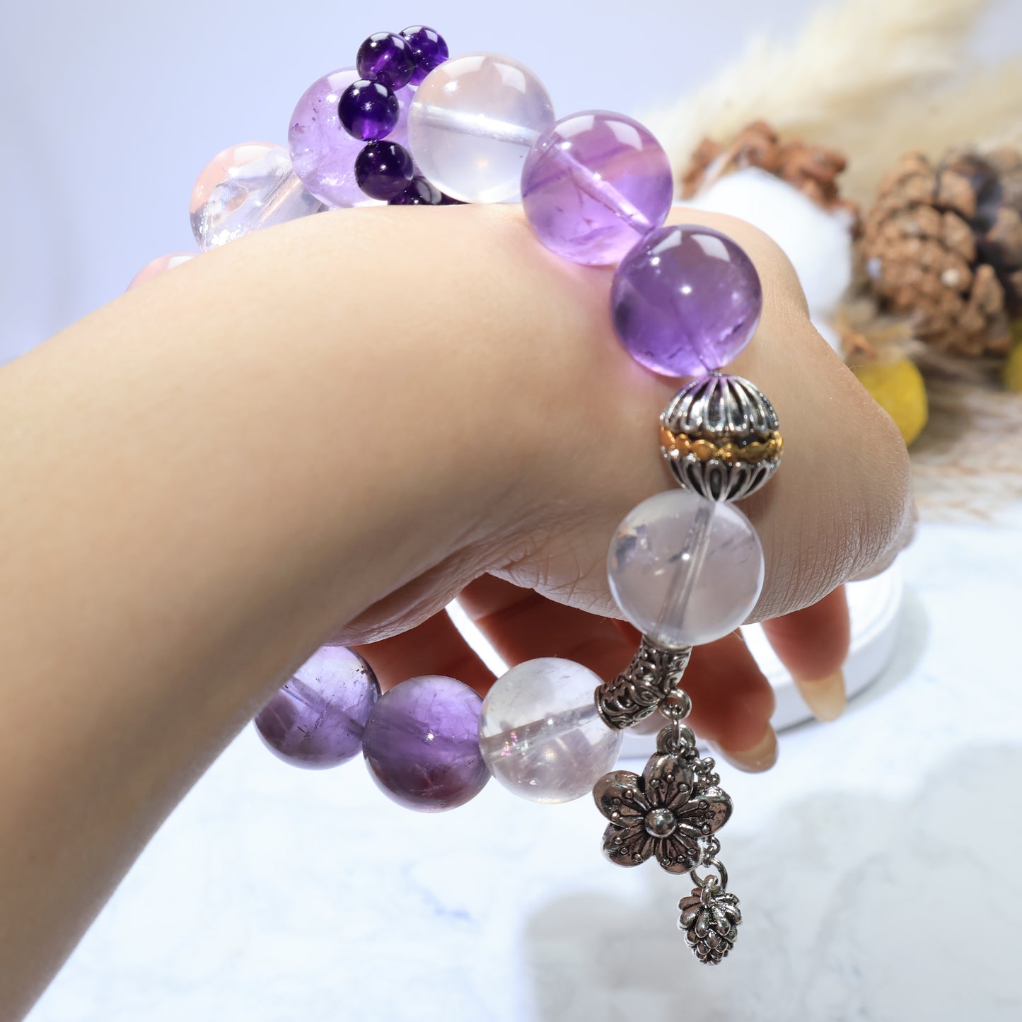 Side wrist shot highlighting the copper cap, dangling charms, and alternating rose quartz–amethyst rhythm.