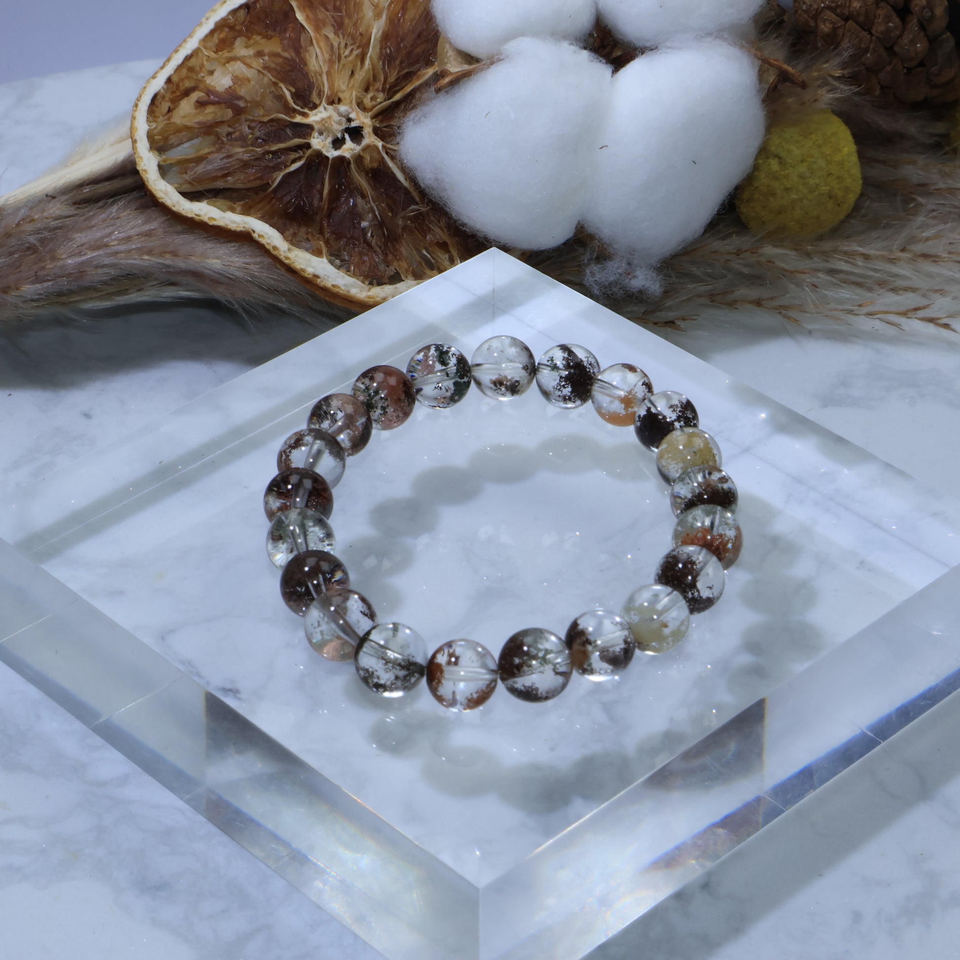 Scenic Phantom Quartz bracelet displayed on acrylic block with dried citrus and cotton decor