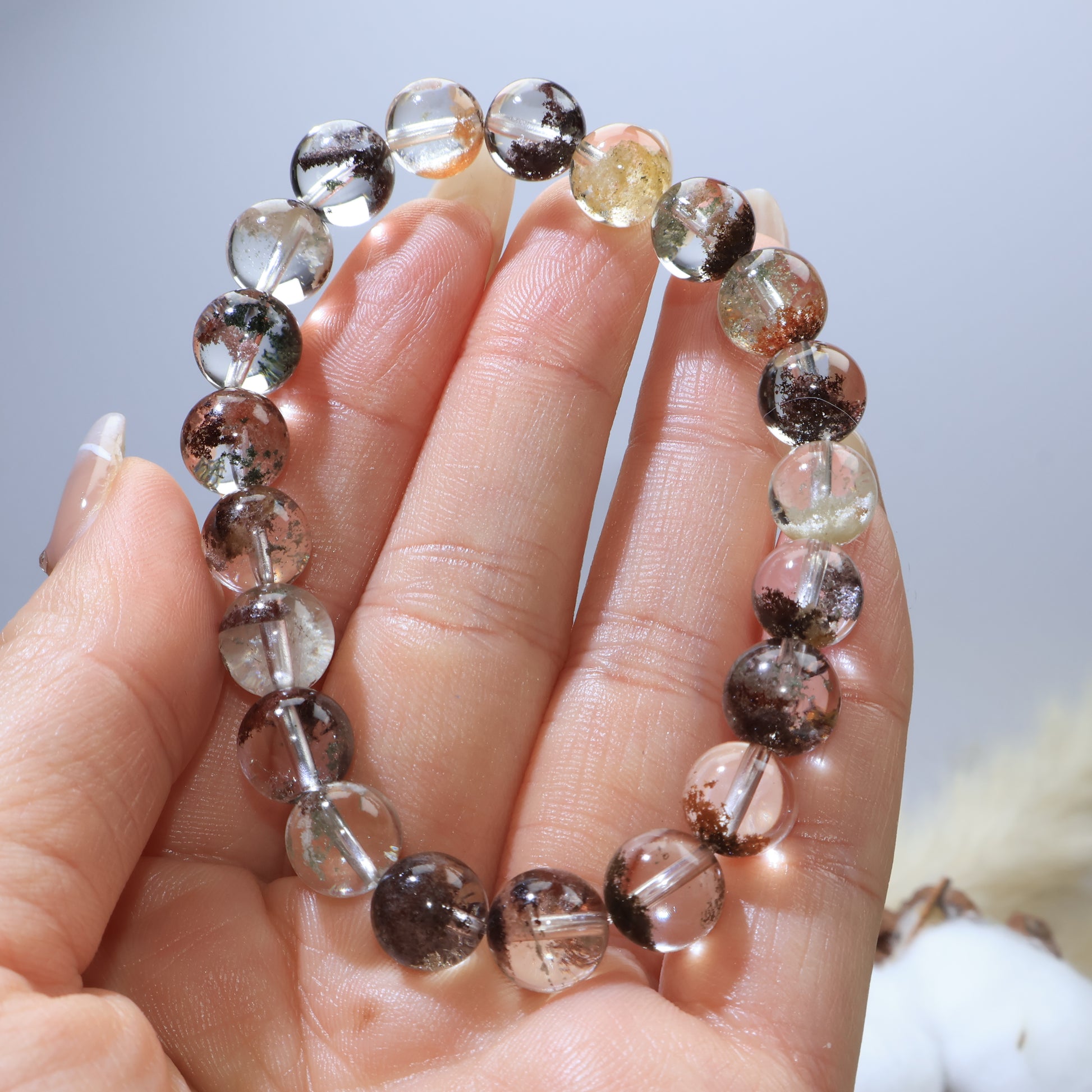 Handheld view of Scenic Phantom Quartz bracelet, highlighting crystal clarity and color variations