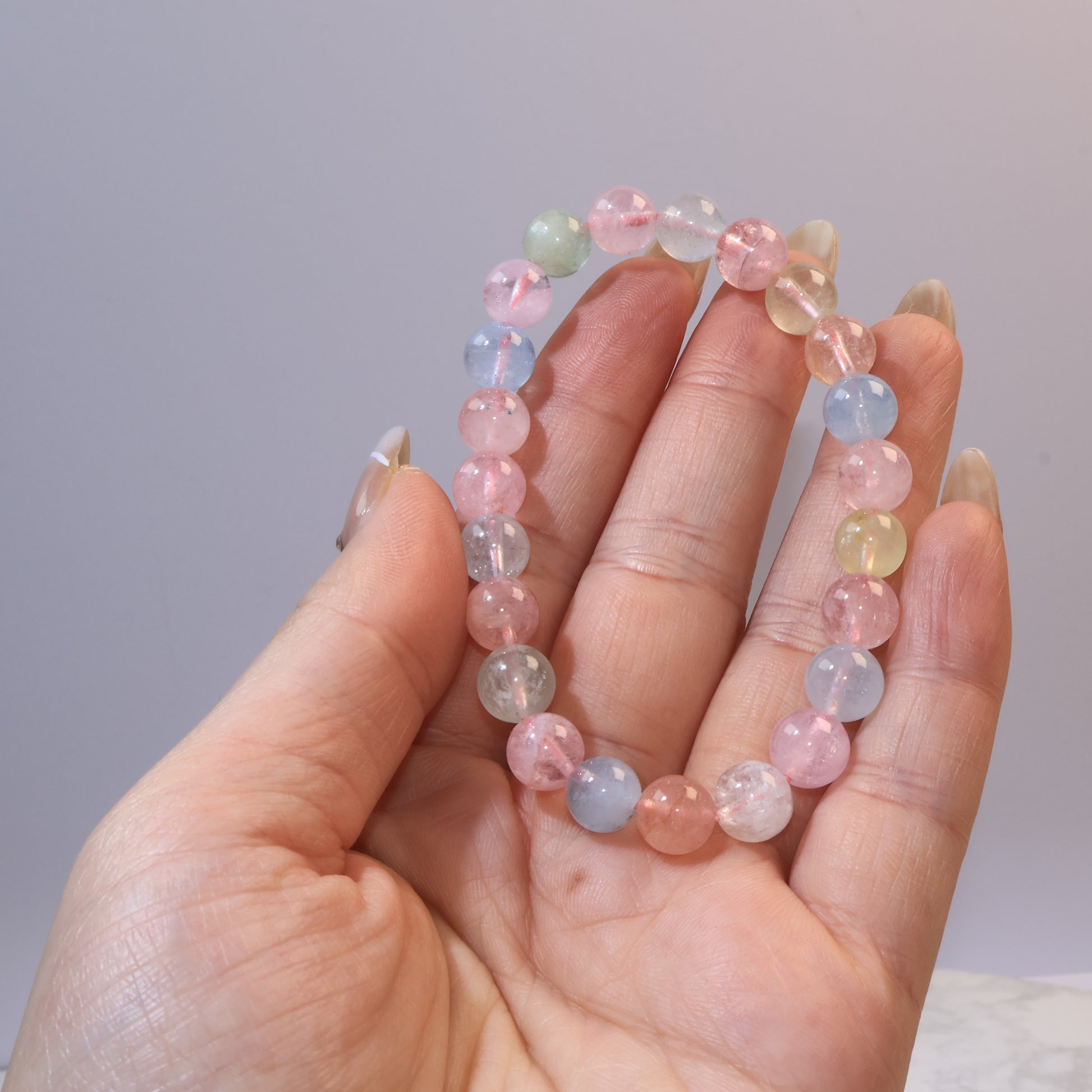 Hand holding Rainbow Morganite bracelet showing pink, blue, green, and yellow tones