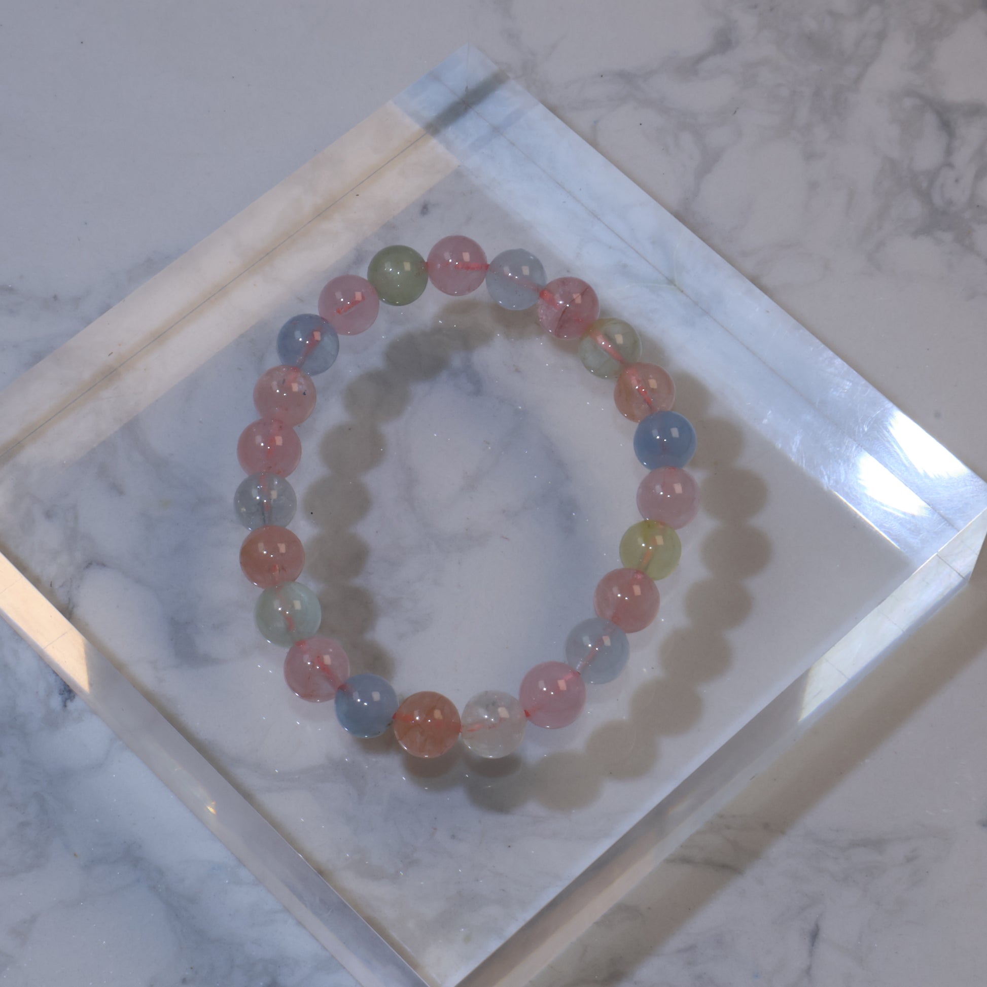 Top view of Rainbow Morganite bracelet with soft pastel beads on clear acrylic block