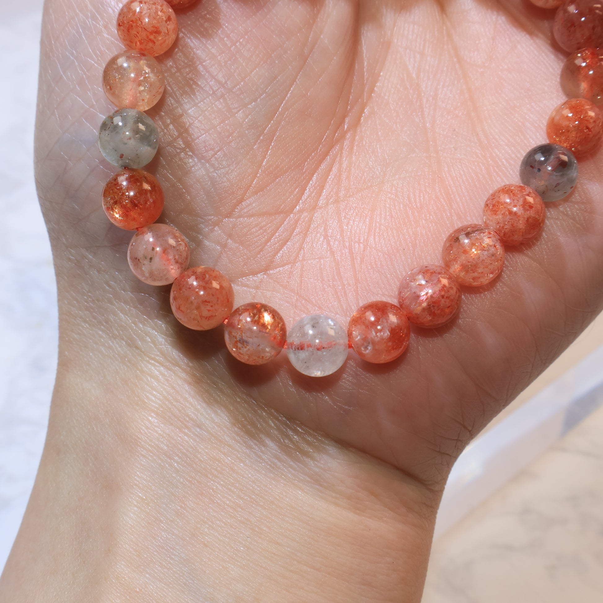 Close-up of Arusha Sunstone bracelet on wrist showing bright reddish-orange hues
