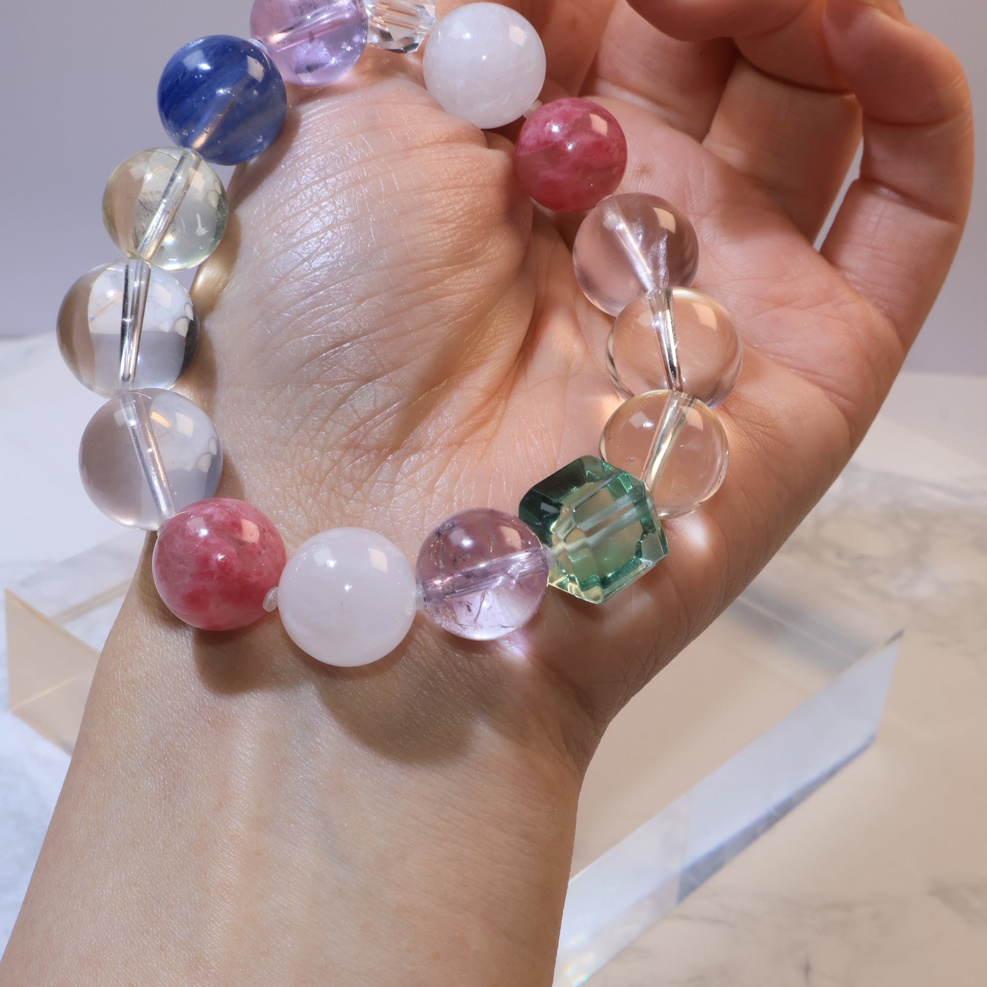 Bracelet draped over wrist highlighting square green fluorite bead and surrounding stones