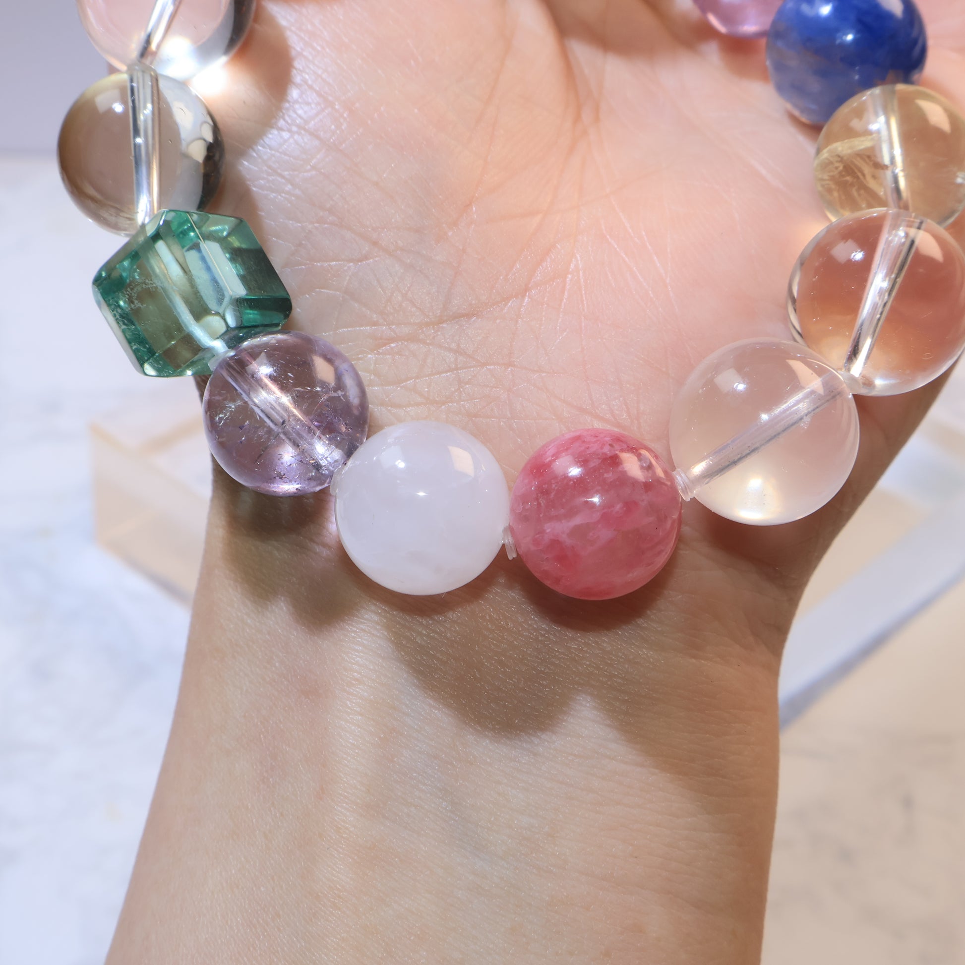 Close-up wrist shot showing rose quartz and red rhodochrosite beads with soft light reflection