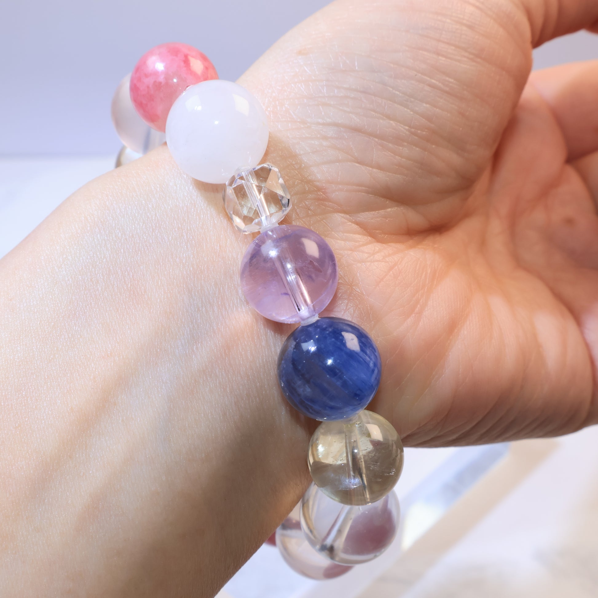 Close-up showing blue kyanite bead next to amethyst and clear quartz faceted bead
