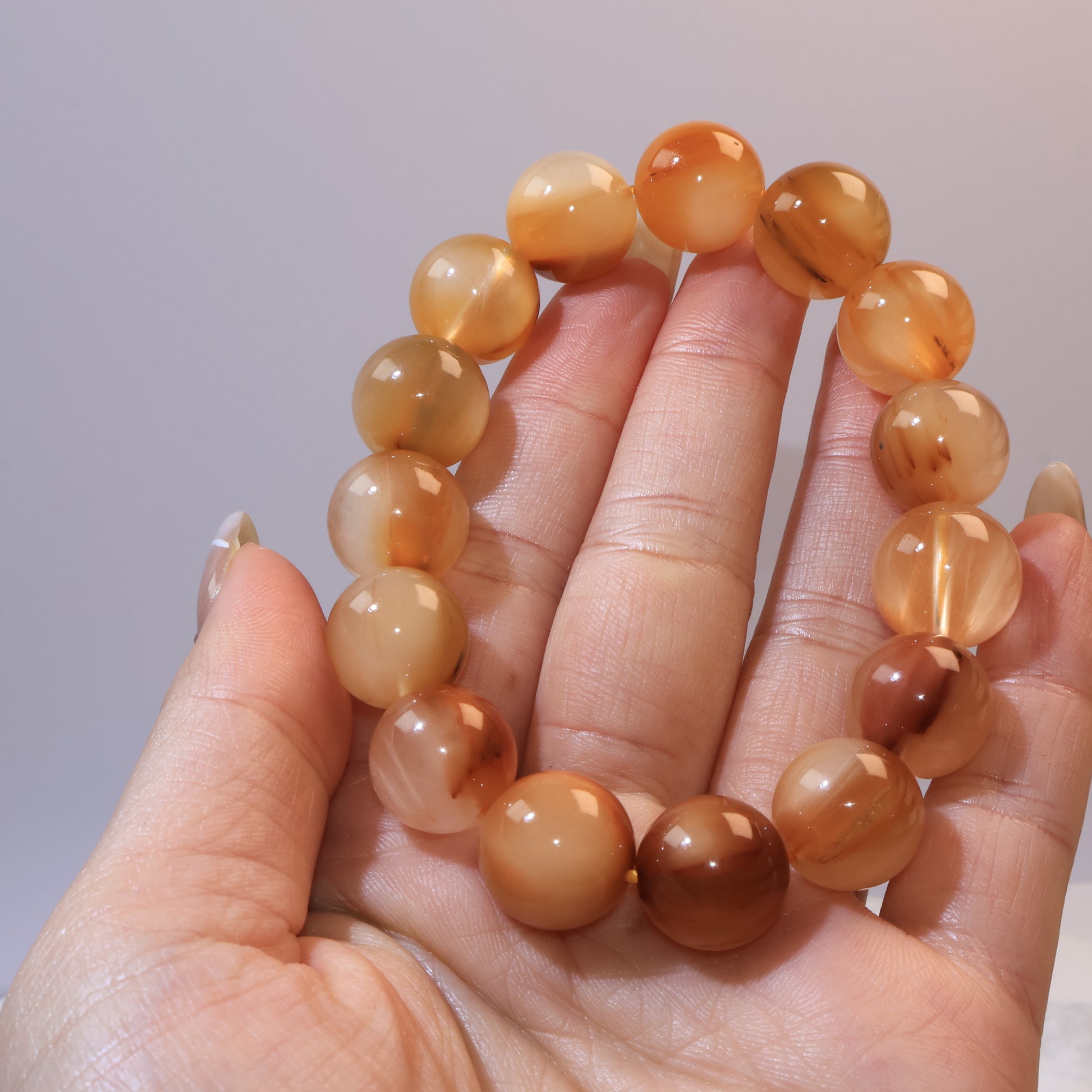 Yellow Rabbit Hair Quartz bracelet displayed on fingers, showing bead size, warm luster, and brown filament patterns