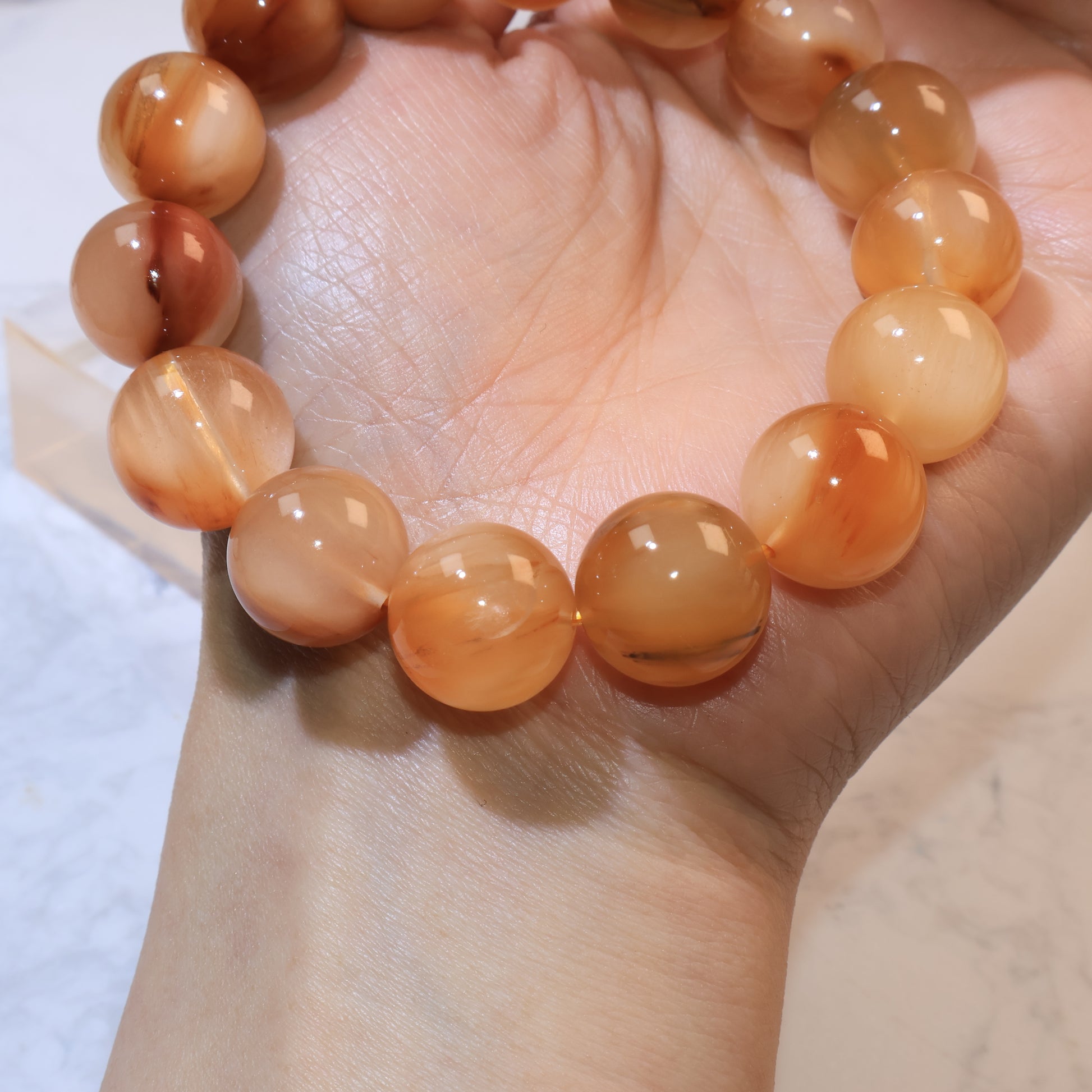 Wrist shot of Yellow Rabbit Hair Quartz bracelet with light reflecting on beads and showing internal brown filaments