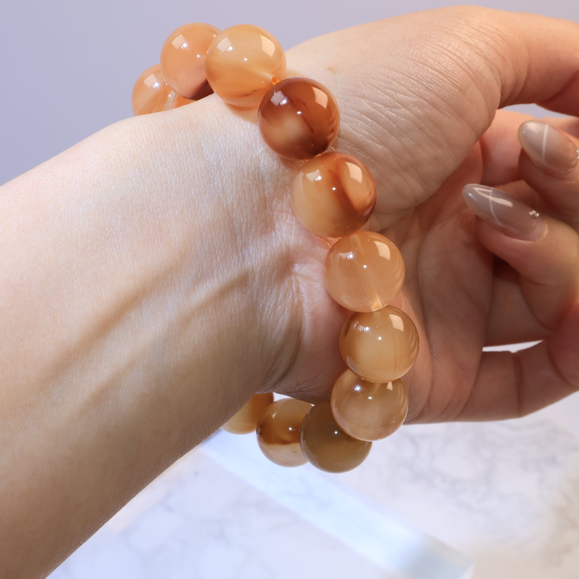 Hand holding Yellow Rabbit Hair Quartz bracelet to display bead alignment, shine, and brown inclusions