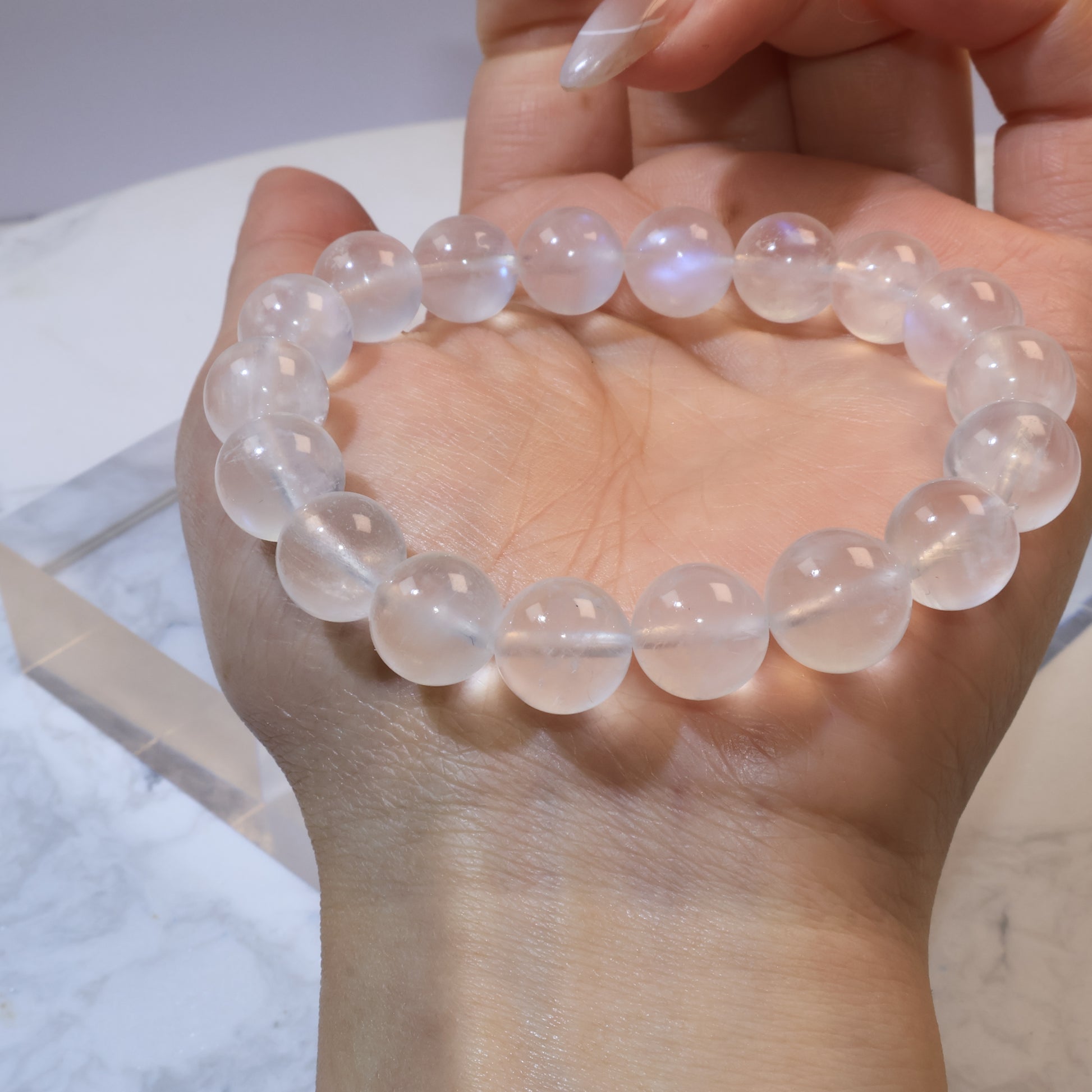 Moonstone bracelet resting across palm, blue sheen visible on several beads
