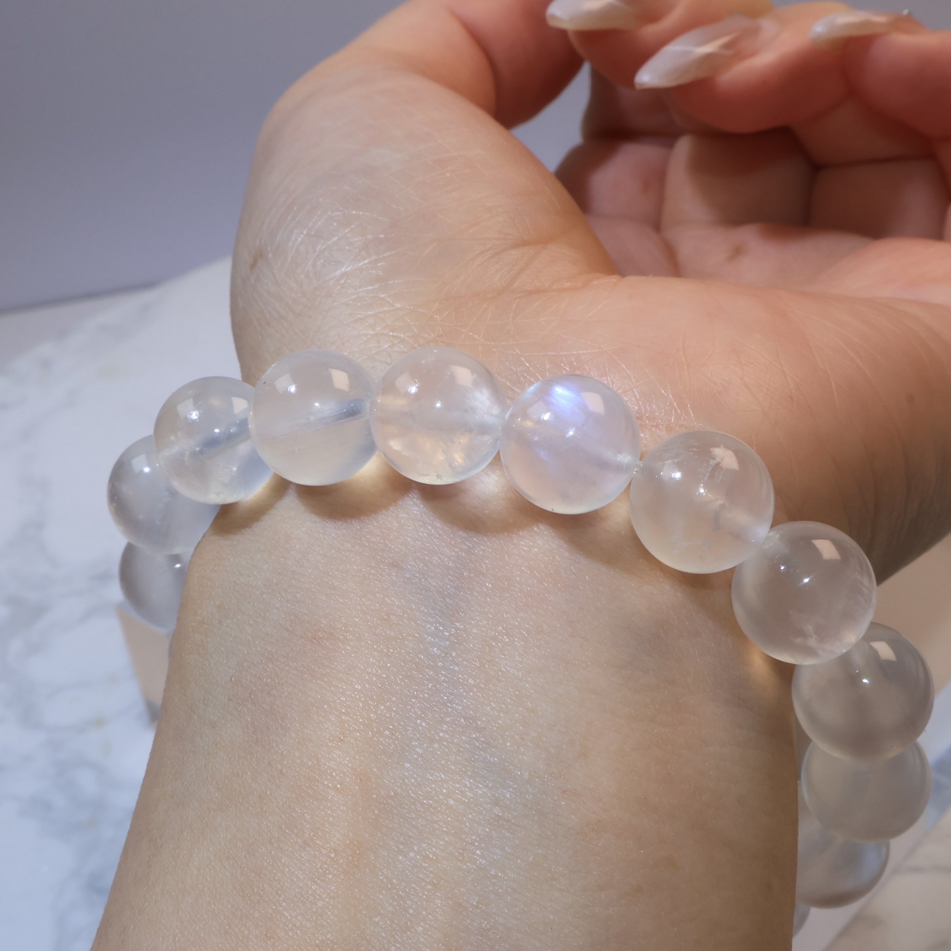 Side wrist view of moonstone bracelet, highlighting blue and white flashes