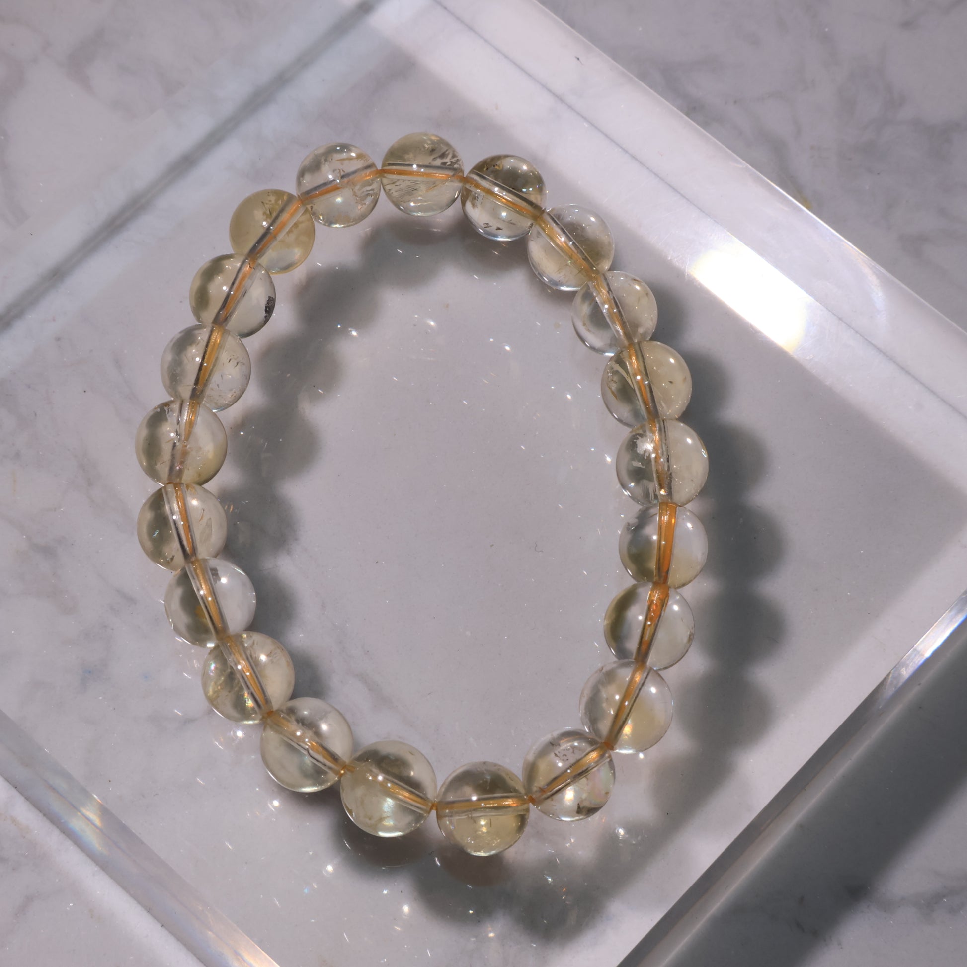 Citrine bracelet with 9mm beads in soft golden tones, displayed on marble background.