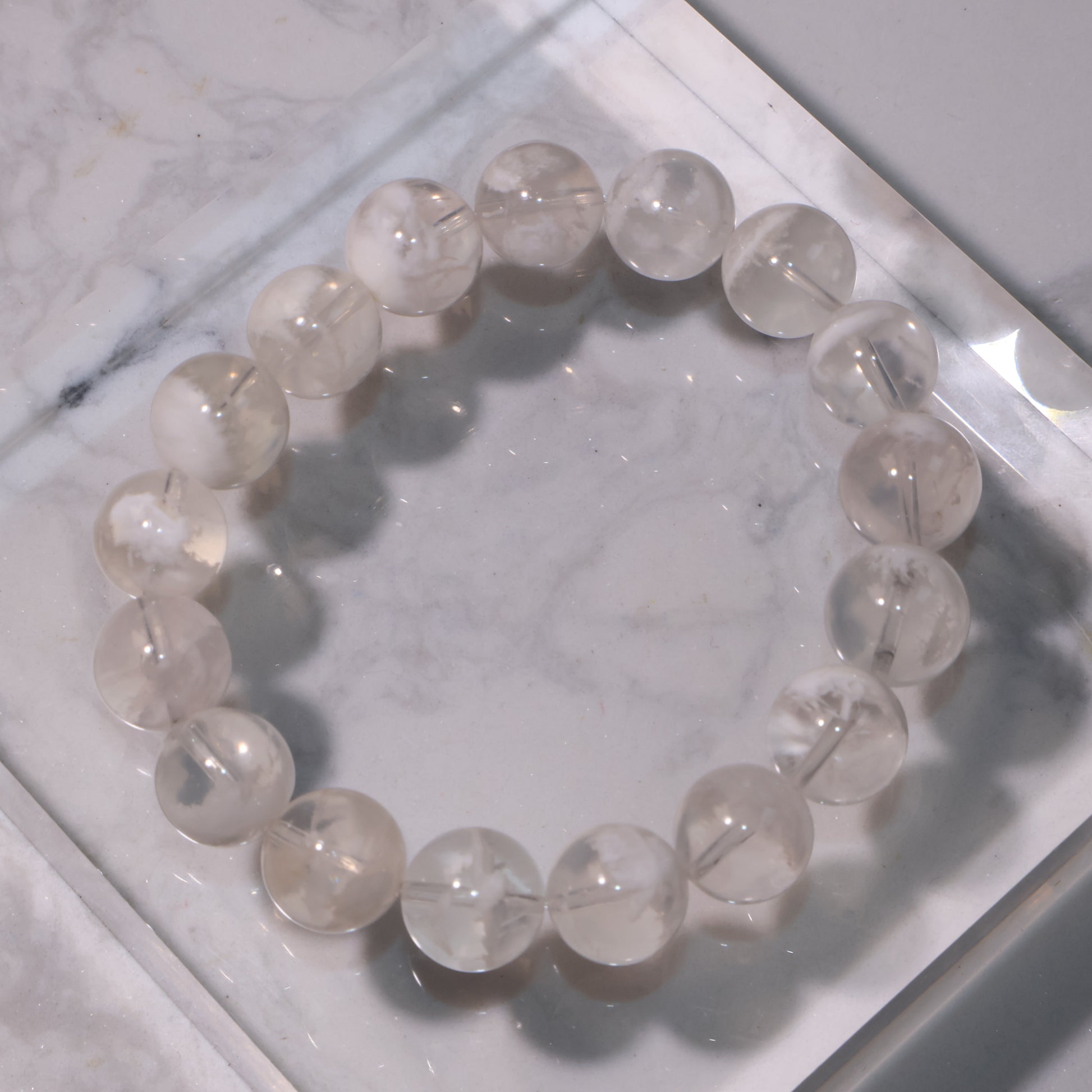 White Phantom Quartz bracelet displayed on marble surface, showing snowy-white phantom inclusions.