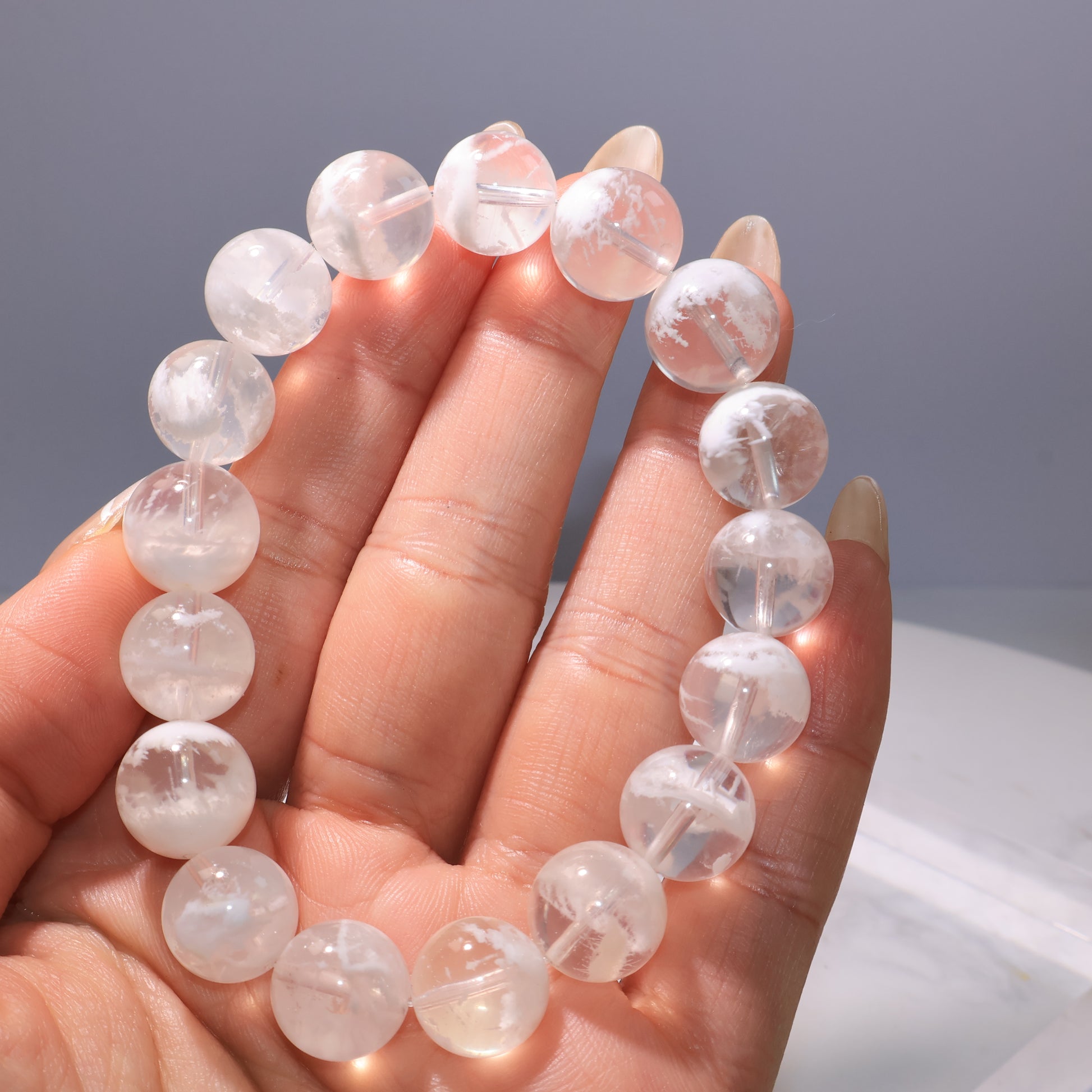 Elegant hand shot wearing White Phantom Quartz bracelet, showing clarity and texture.