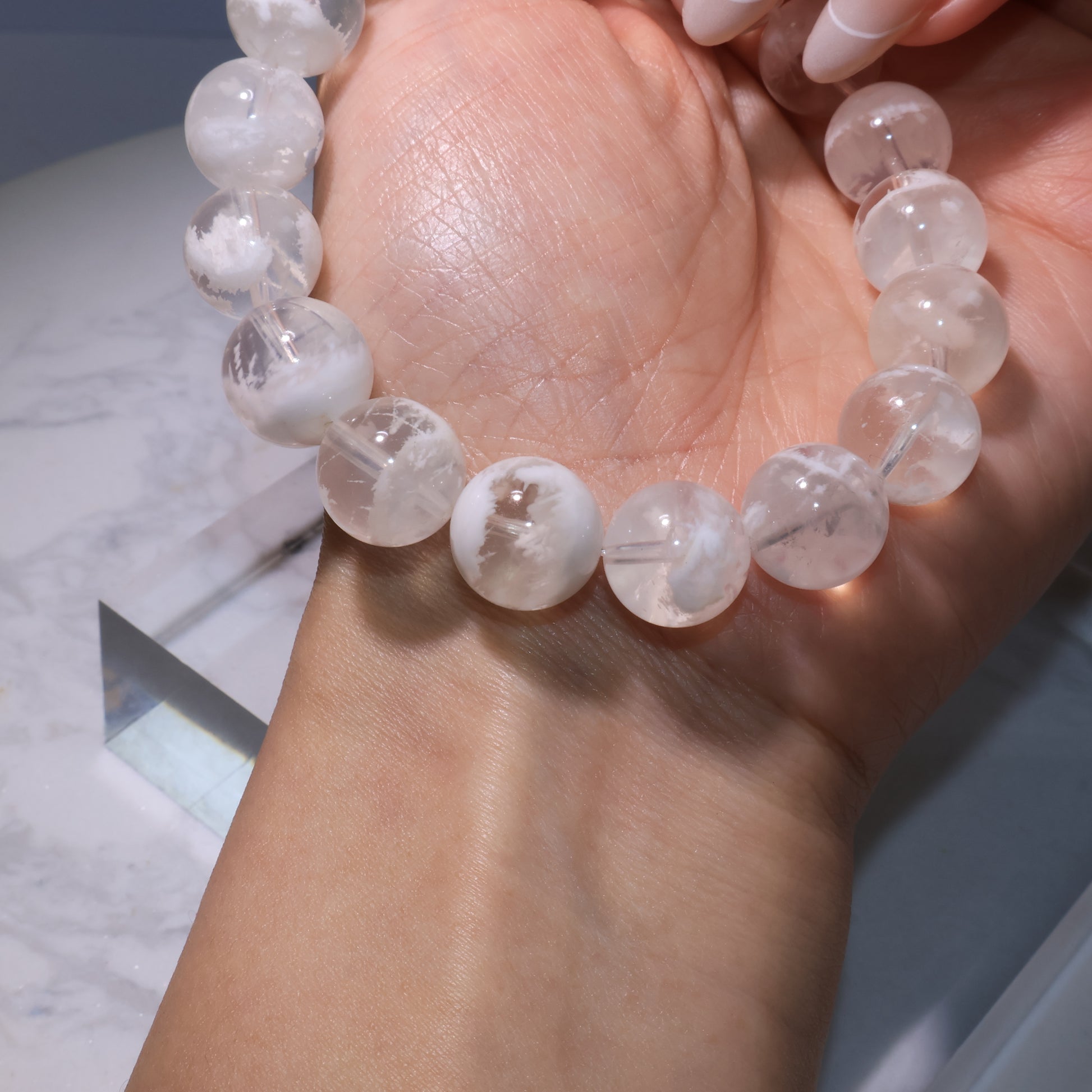 Bracelet side view on wrist, beads displaying romantic snowy-white phantoms.