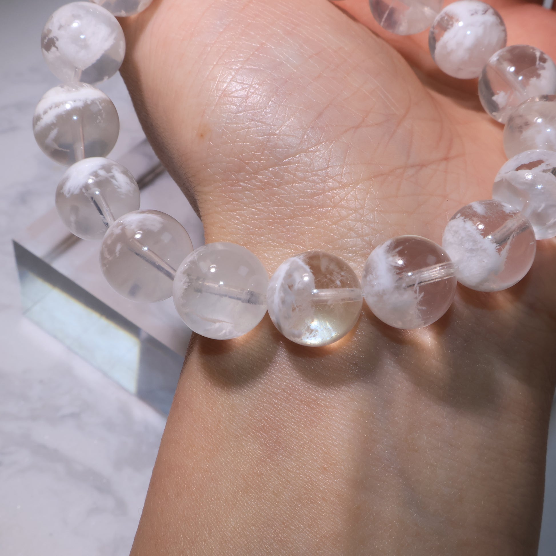 Close-up of White Phantom Quartz bracelet on wrist, showing mist-like structures inside.