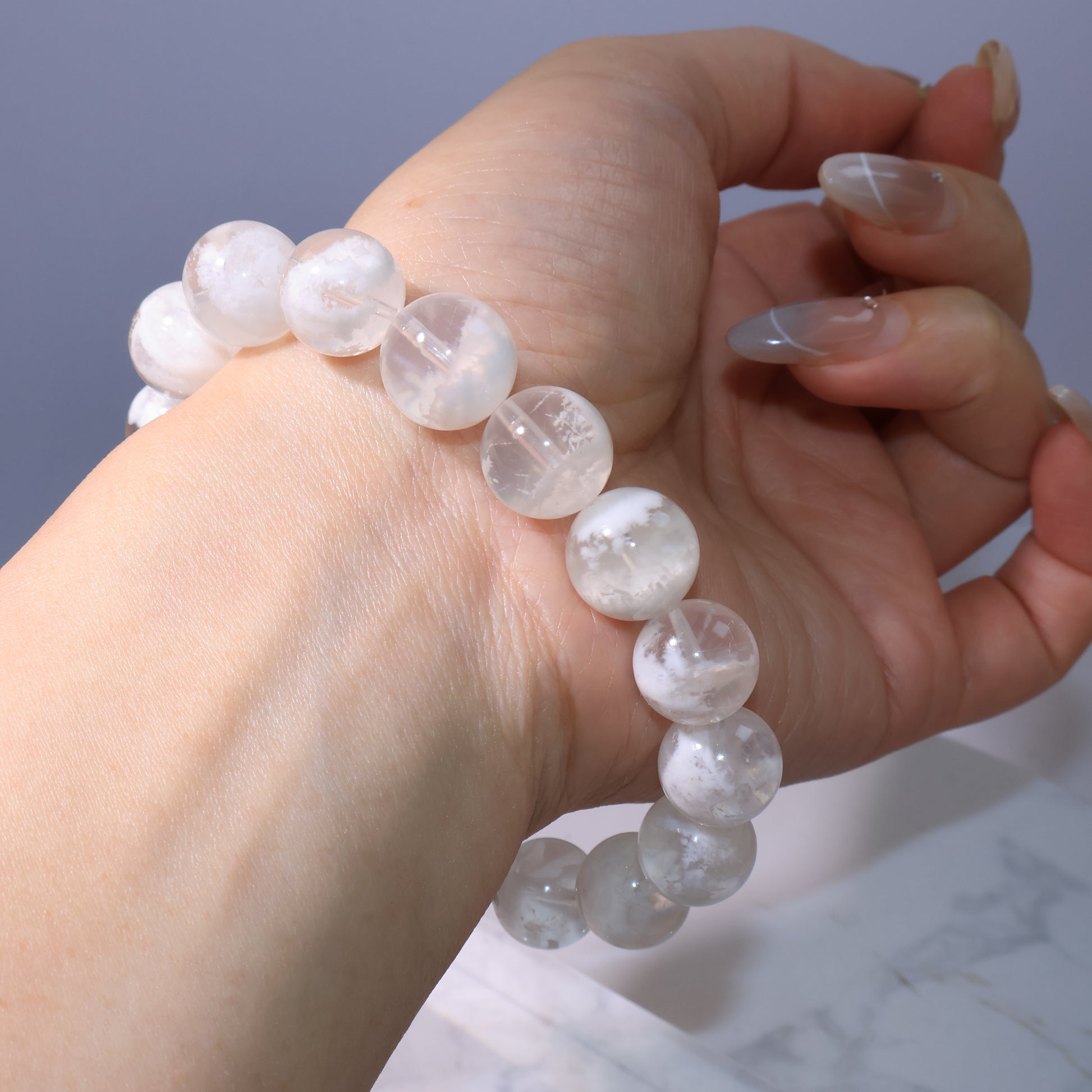 Bracelet side view on wrist, beads displaying romantic snowy-white phantoms.