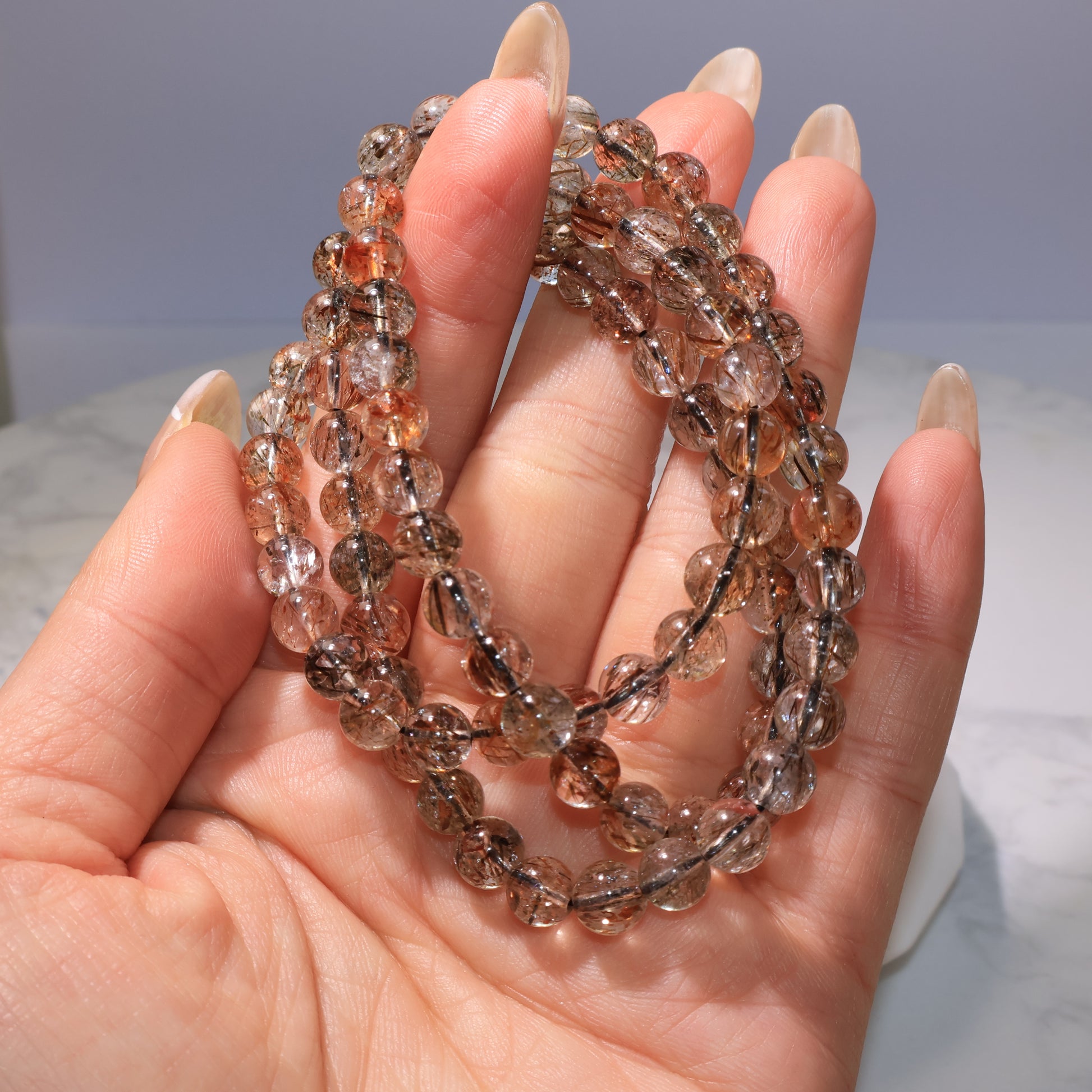 Bracelet held in hand, showing sparkling rutile inclusions|手持展示,清晰可見髮絲晶體