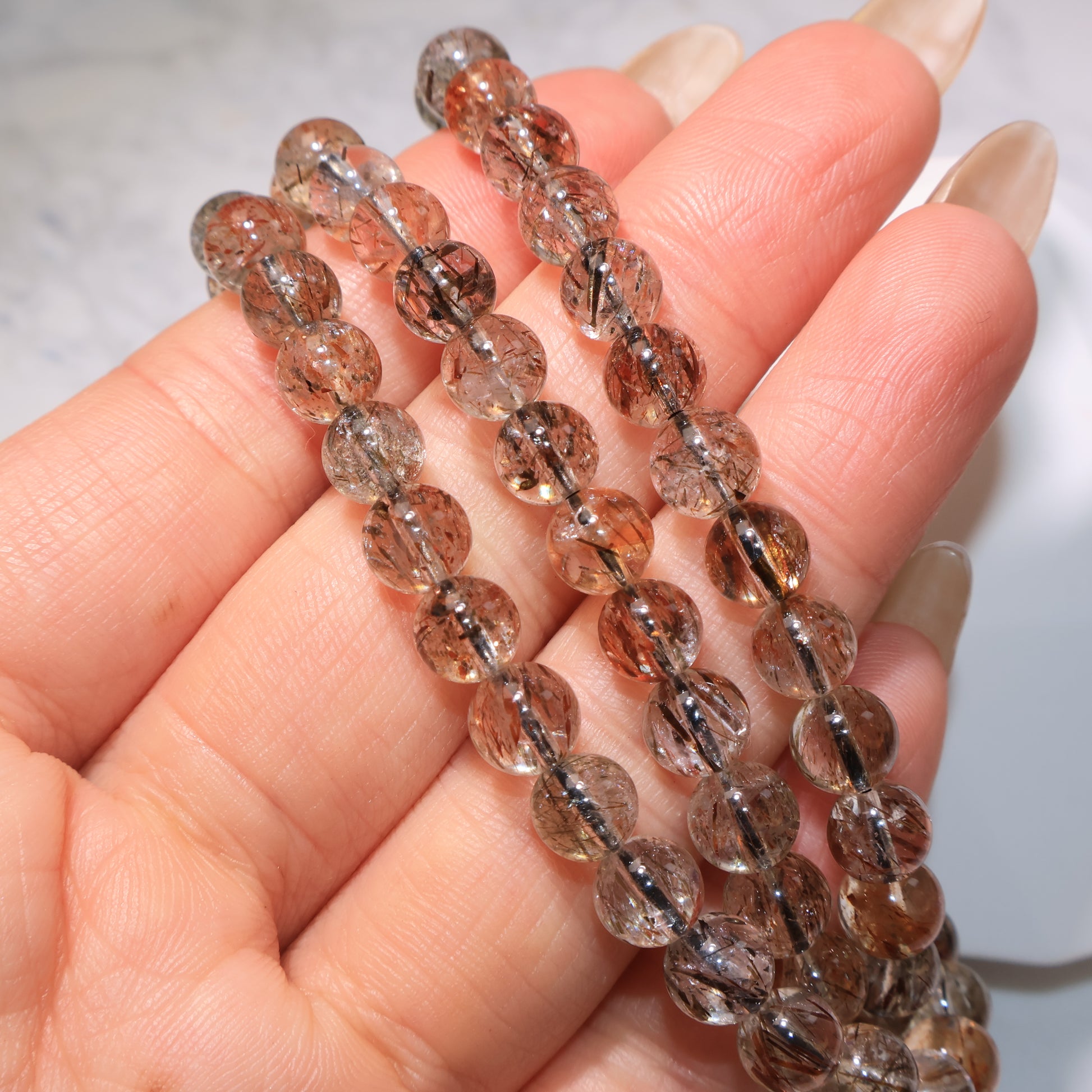 Close-up of beads showing red-gold and black rutile needles|珠子特寫,顯示金紅與黑色髮絲