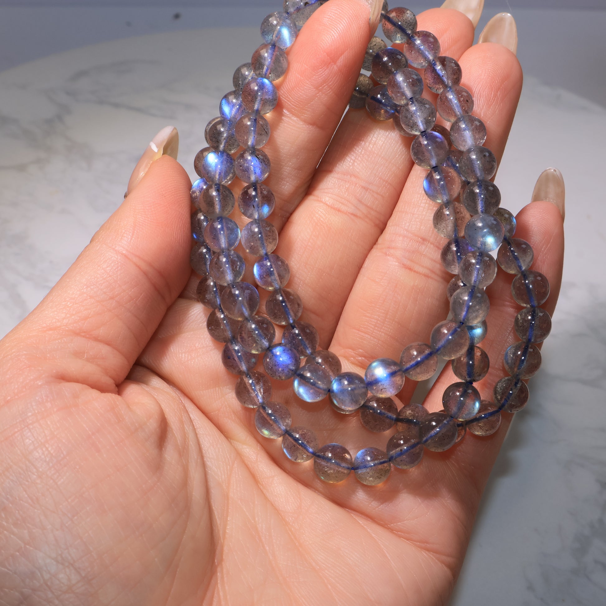 Hand holding bracelet, showing vivid blue labradorescence|手持展示,強烈藍光一覽無遺