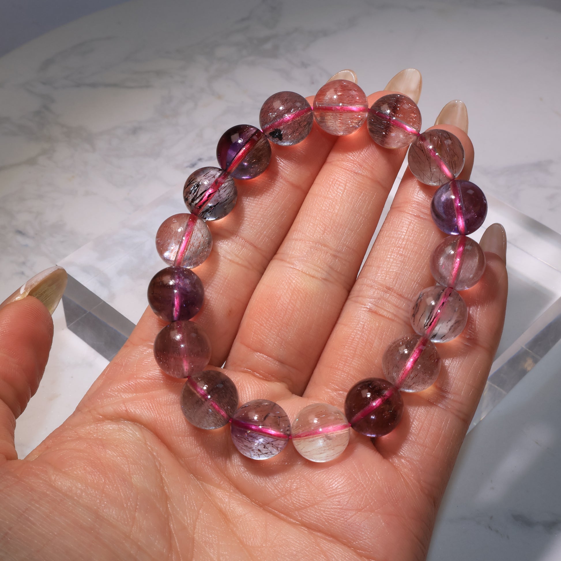 Bracelet held in hand, showing inclusions and natural zoning|手持超七手串,展現晶體內部髮絲與色帶