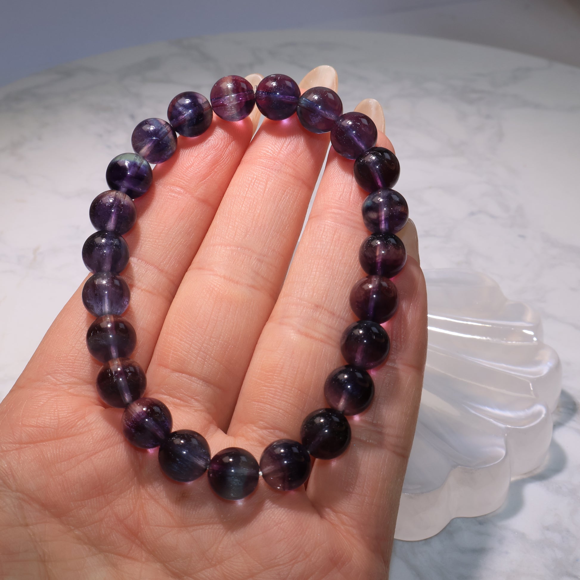 Fluorite bracelet held in hand, showing transparency and mixed purple-blue colors.