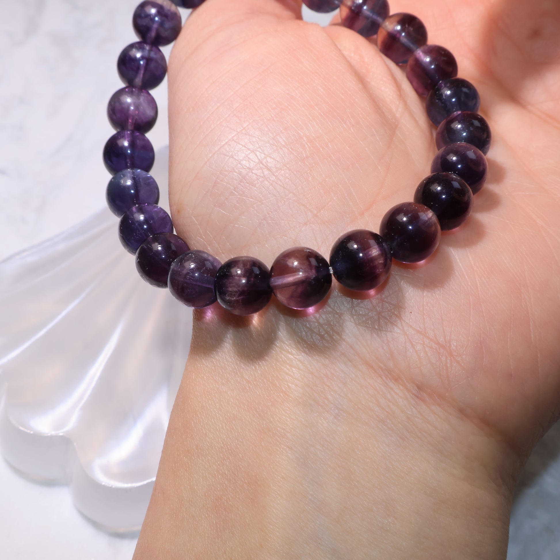 Fluorite bracelet resting on palm, beads glowing with purple and green tones