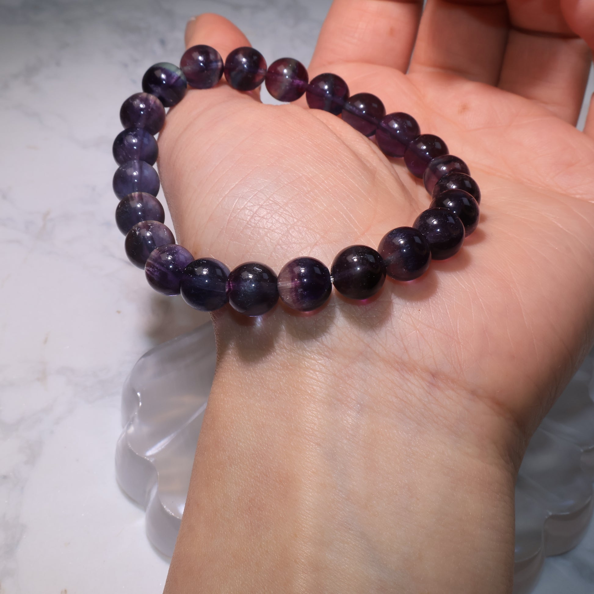 Fluorite bracelet with 8mm beads shown on the palm, highlighting deep purple and blue tones.